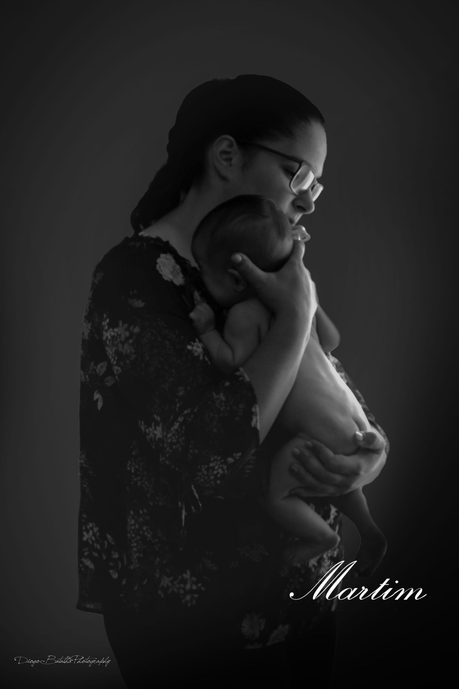 Artistic black and white portrait of someone holding an infant in a gentle embrace.