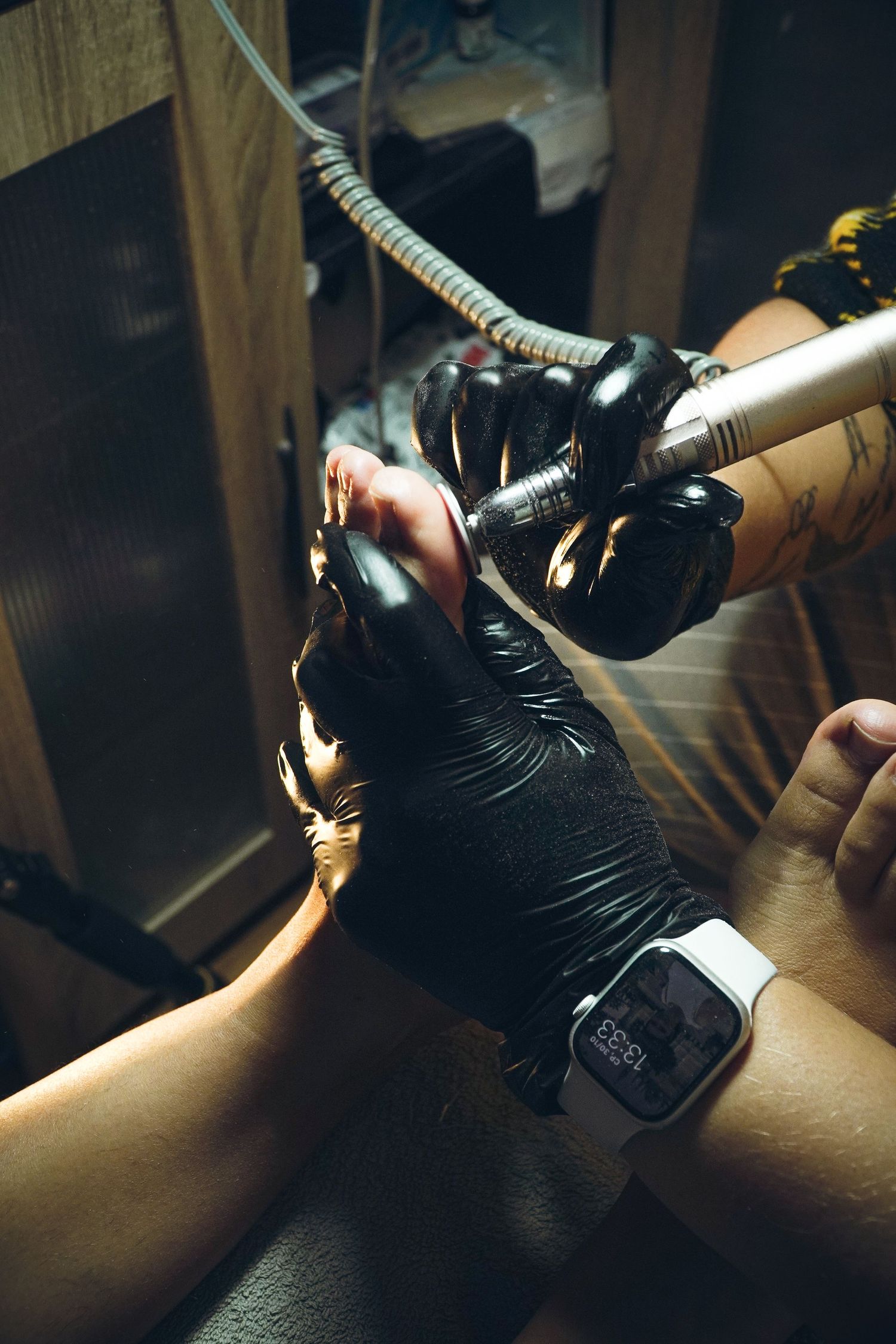 Close-up sequence showing a hand wearing black gloves performing tattoo process in a dimly lit studio.