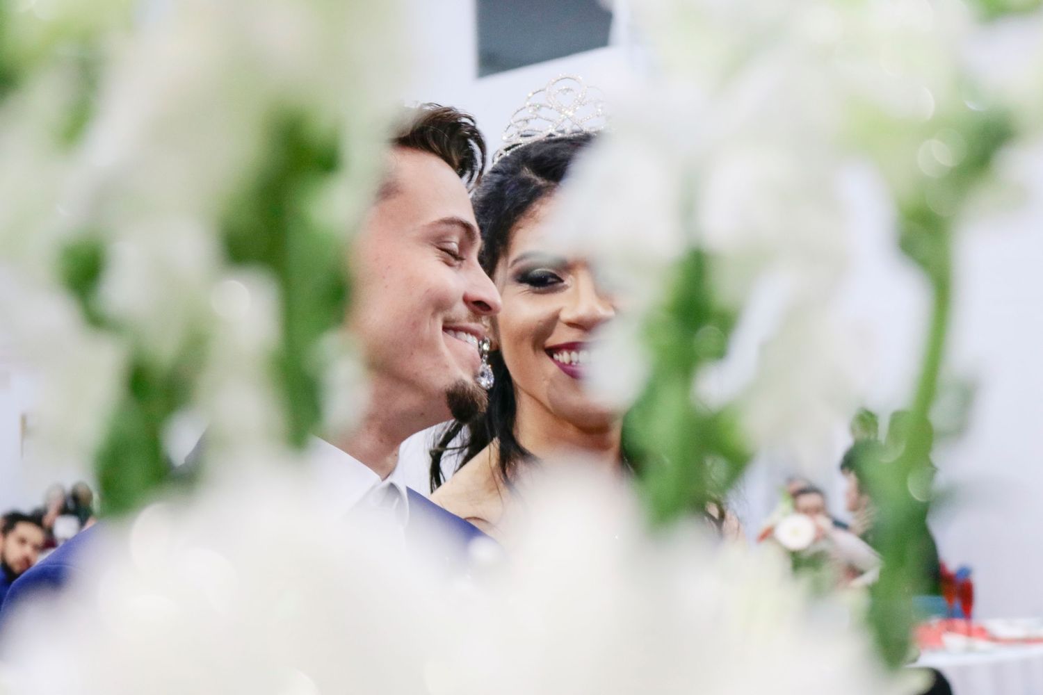 Wedding couple shares tender moment framed by white florals and greenery.