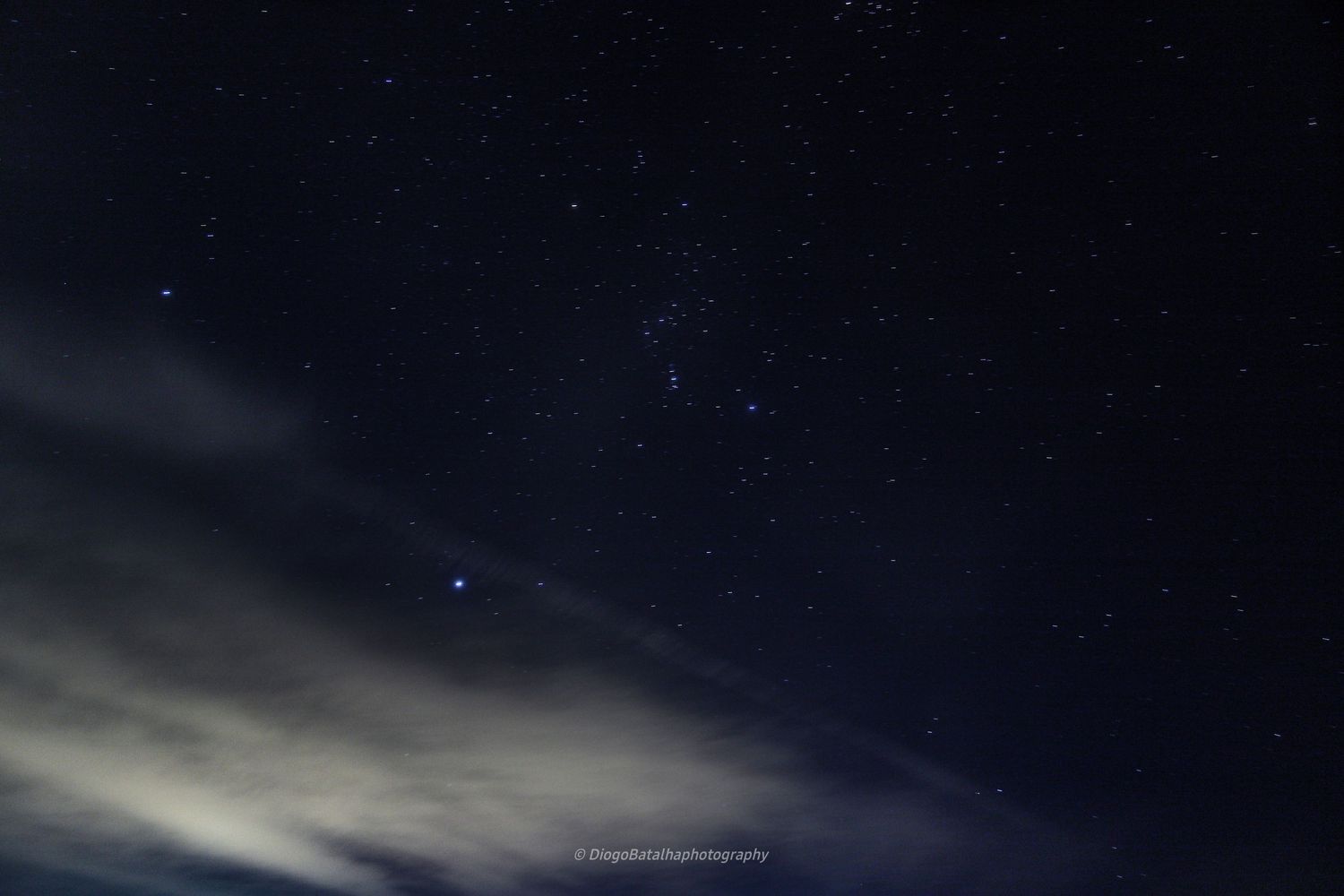 A night sky filled with stars and wispy clouds illuminated by moonlight creates a serene celestial landscape.