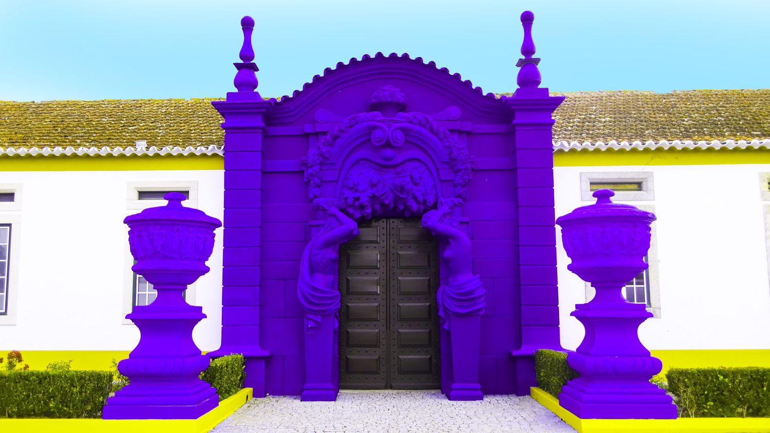 A vibrant purple ornate doorway entrance with white walls and decorative elements stands prominently against a white building.