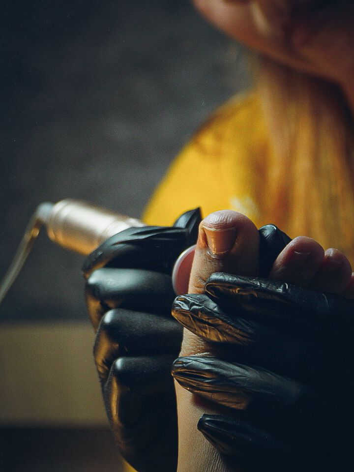 Close-up of hands wearing black gloves preparing or handling something in a dimly lit setting with yellow background.