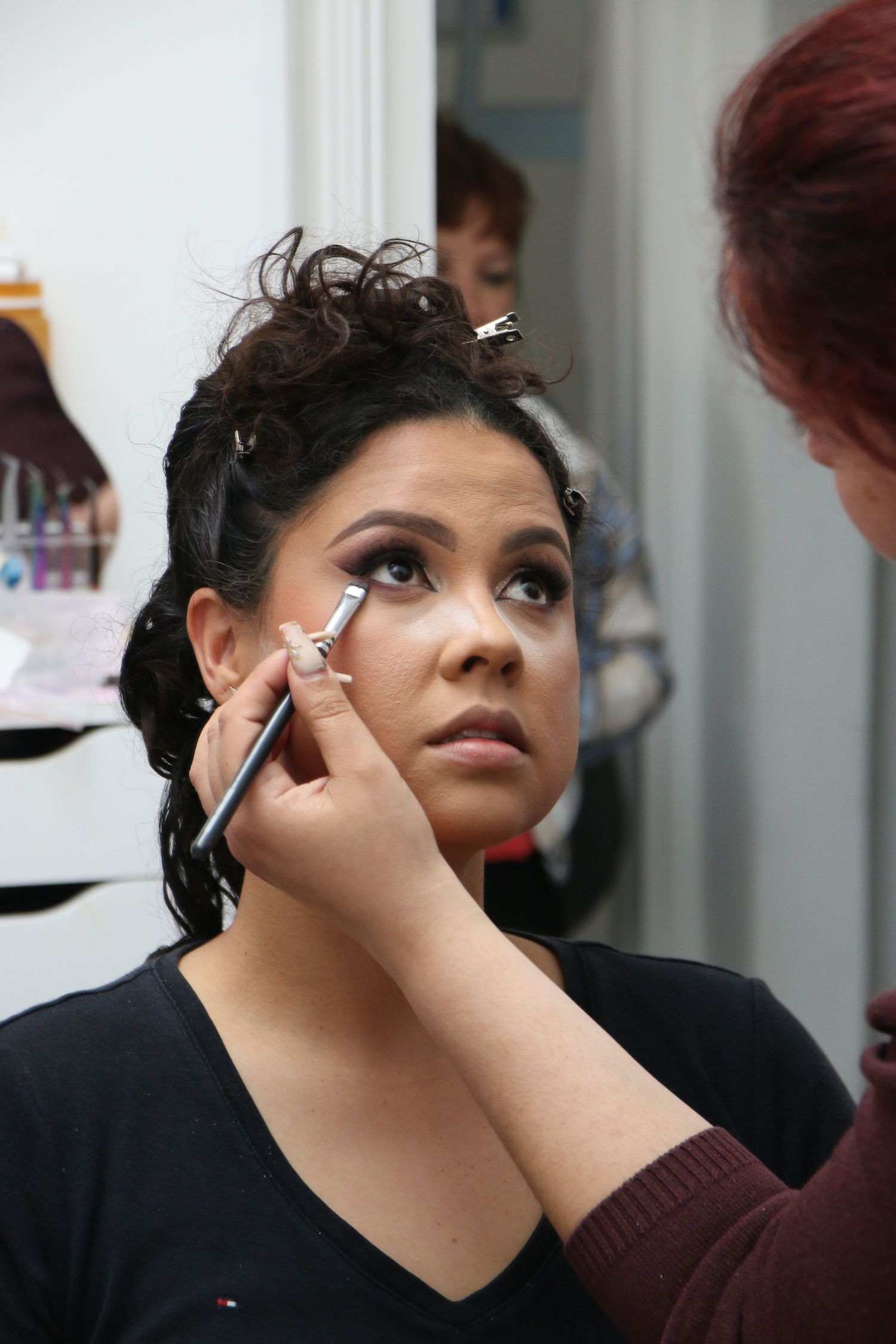 A makeup artist applies eyeshadow to someone's face during a professional beauty session.