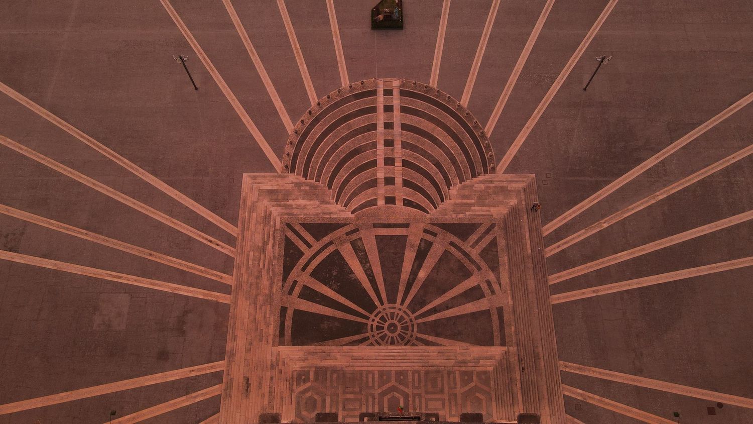 Art deco architectural detail with radiating copper lines forming a sunburst pattern above an ornate doorway entrance.