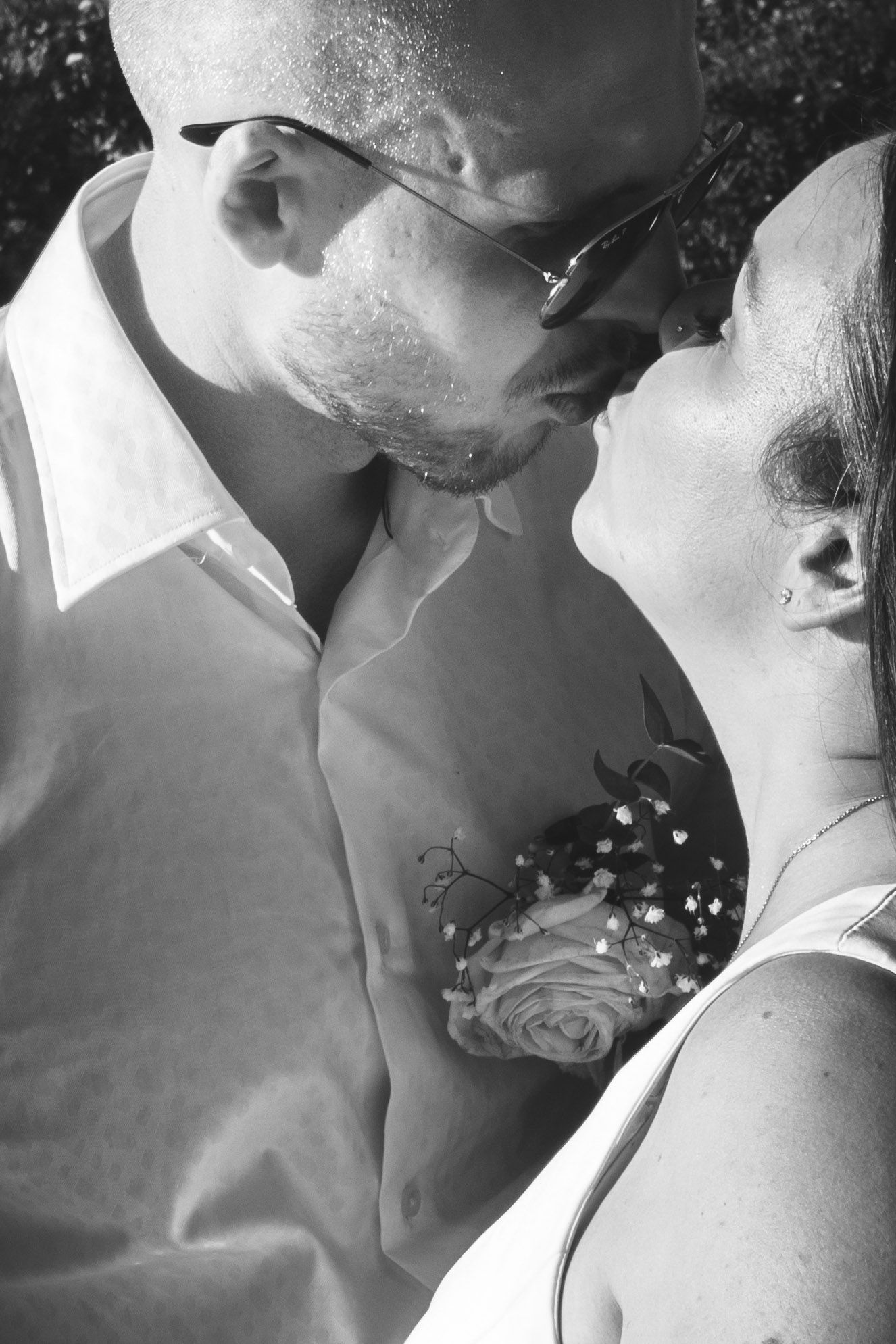 Romantic black and white close-up of couple sharing intimate moment with rose boutonniere.