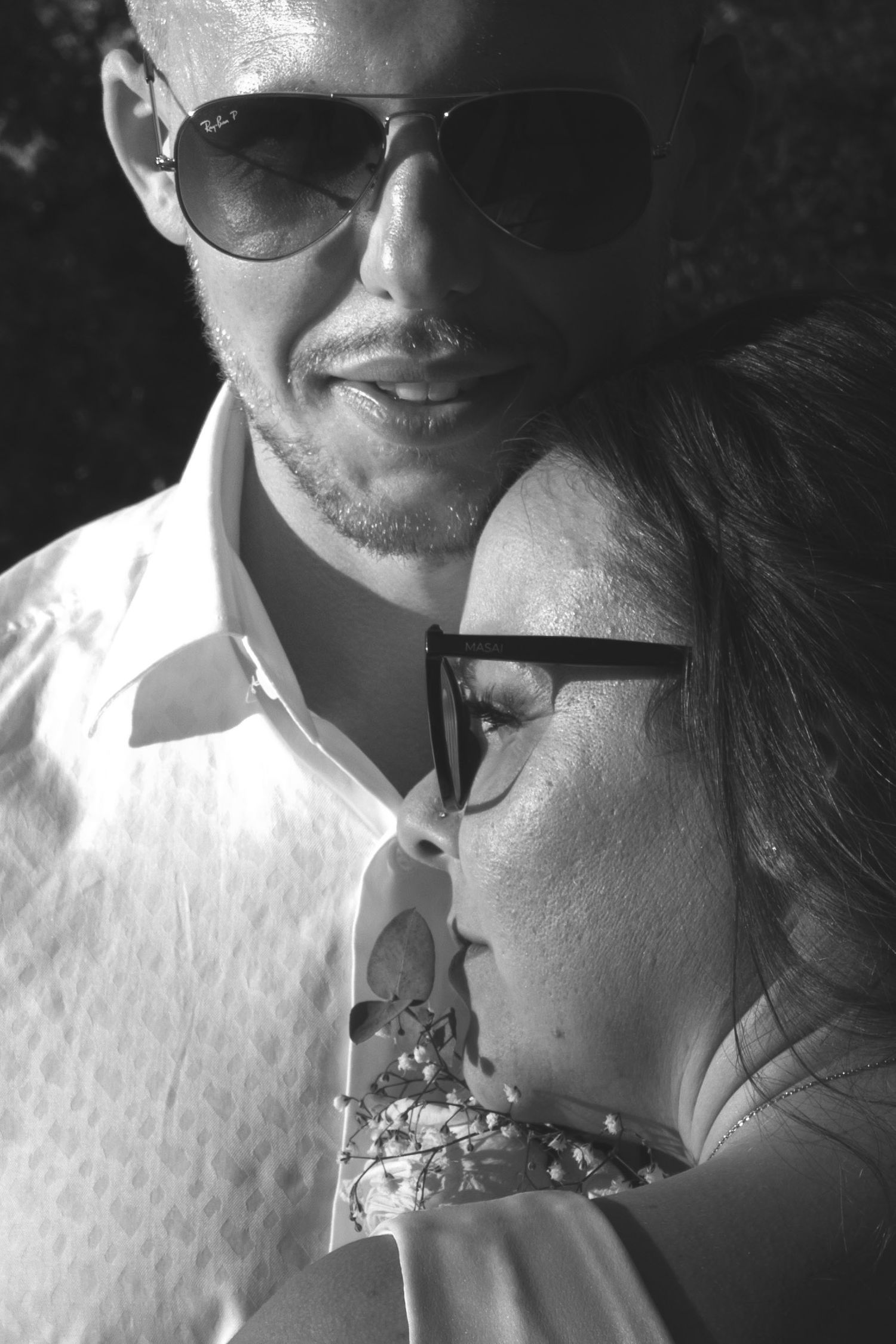 Intimate black and white portrait of couple wearing sunglasses.