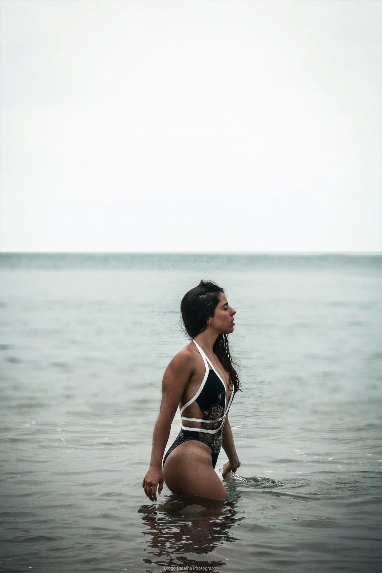 Moody beach photography of person standing in ocean water.