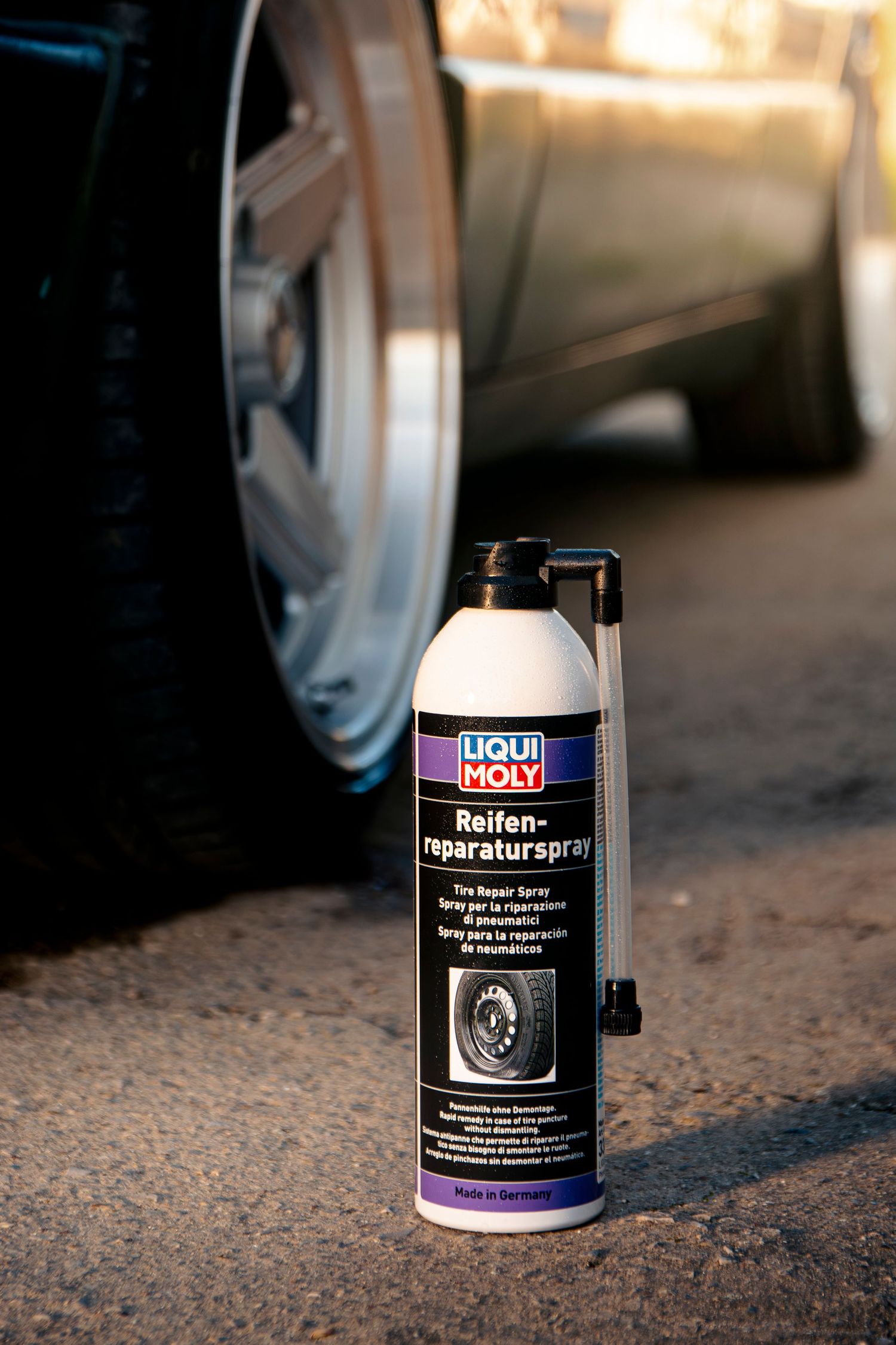 Liqui Moly Reifenreparaturspray tire repair spray can on pavement next to a car tire.