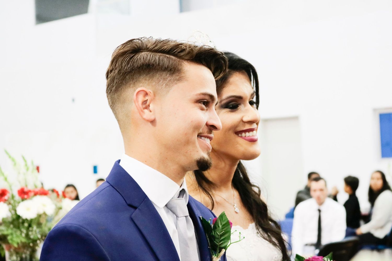 Wedding couple in navy suit and white dress share joyful moment during ceremony.