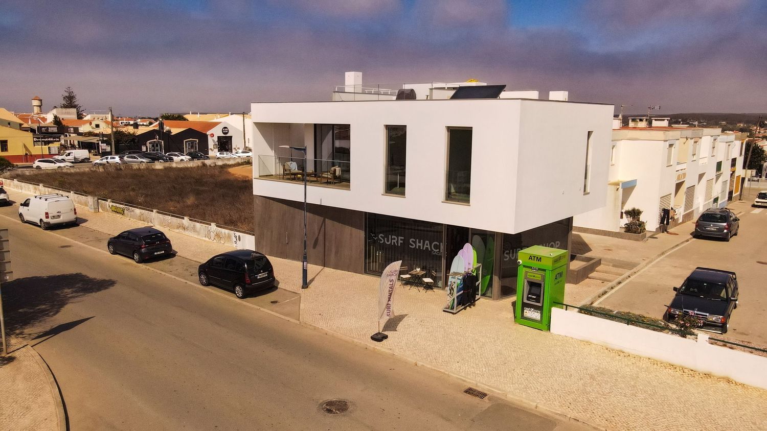 Modern white buildings and architecture against desert landscape with parked cars.