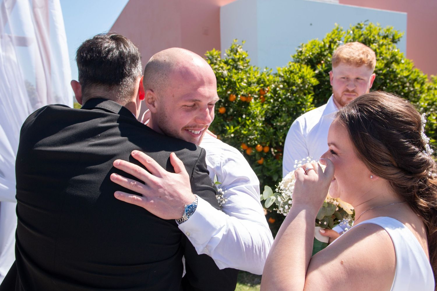 Emotional moment during outdoor wedding ceremony as guests embrace and react.
