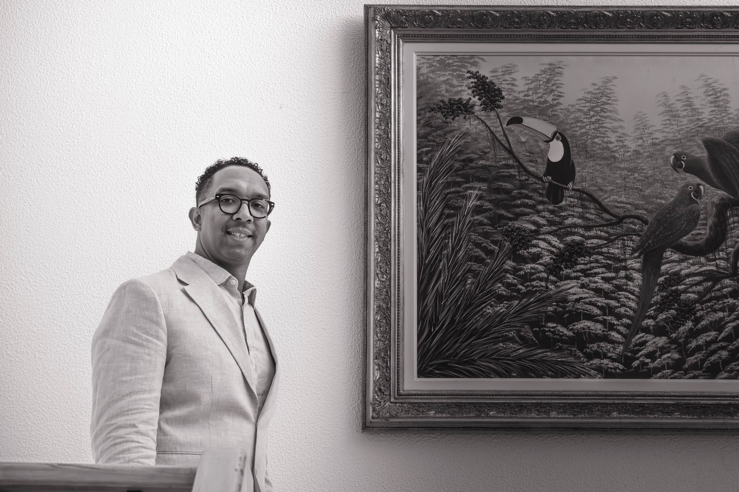 A person in formal attire stands in front of an ornate picture frame at a museum or art gallery.