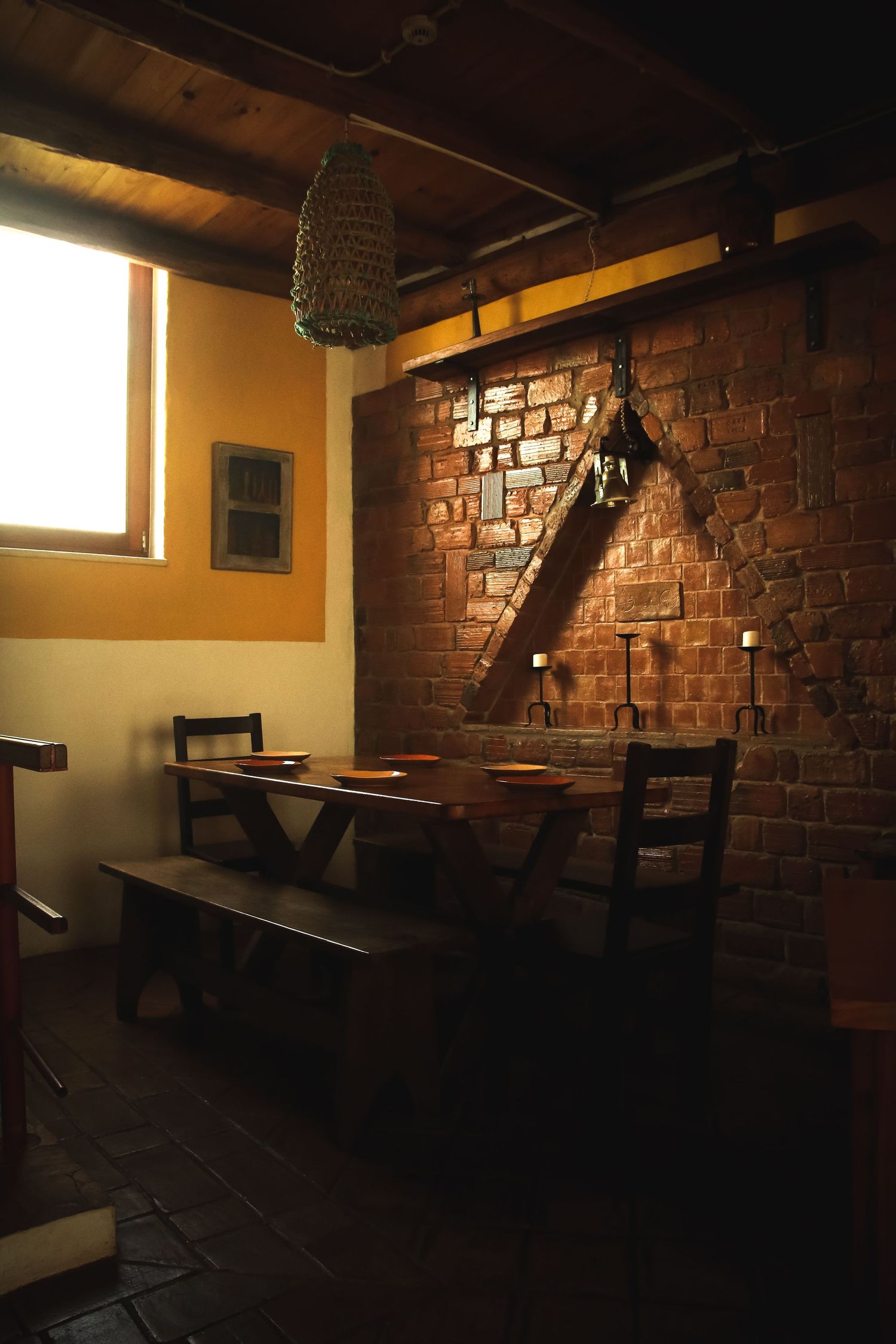 Rustic restaurant corner with exposed brick wall and wooden bench seating.