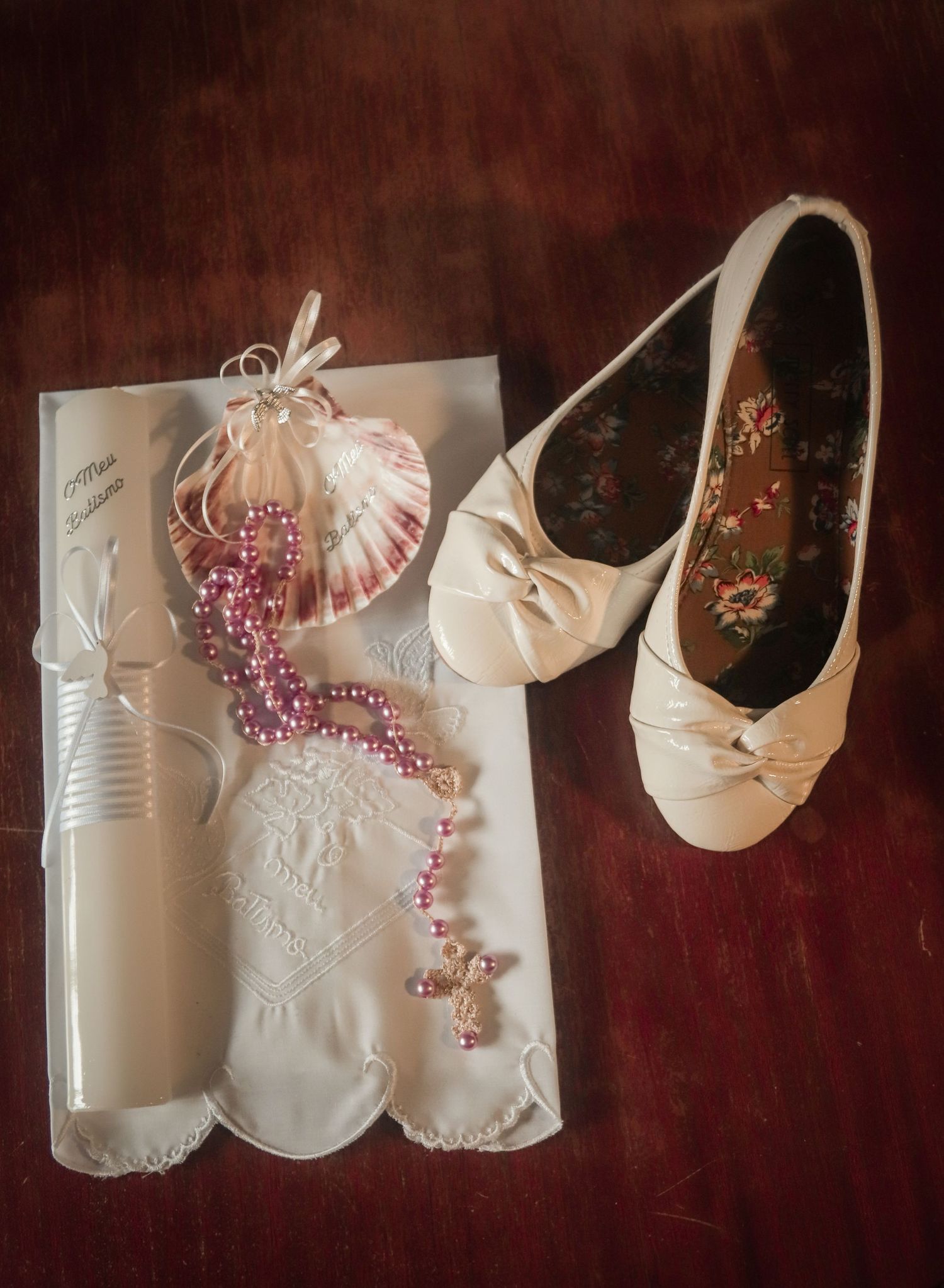 Wedding accessories including white ballet flats, a delicate veil, and pink pearl necklace on a dark background.