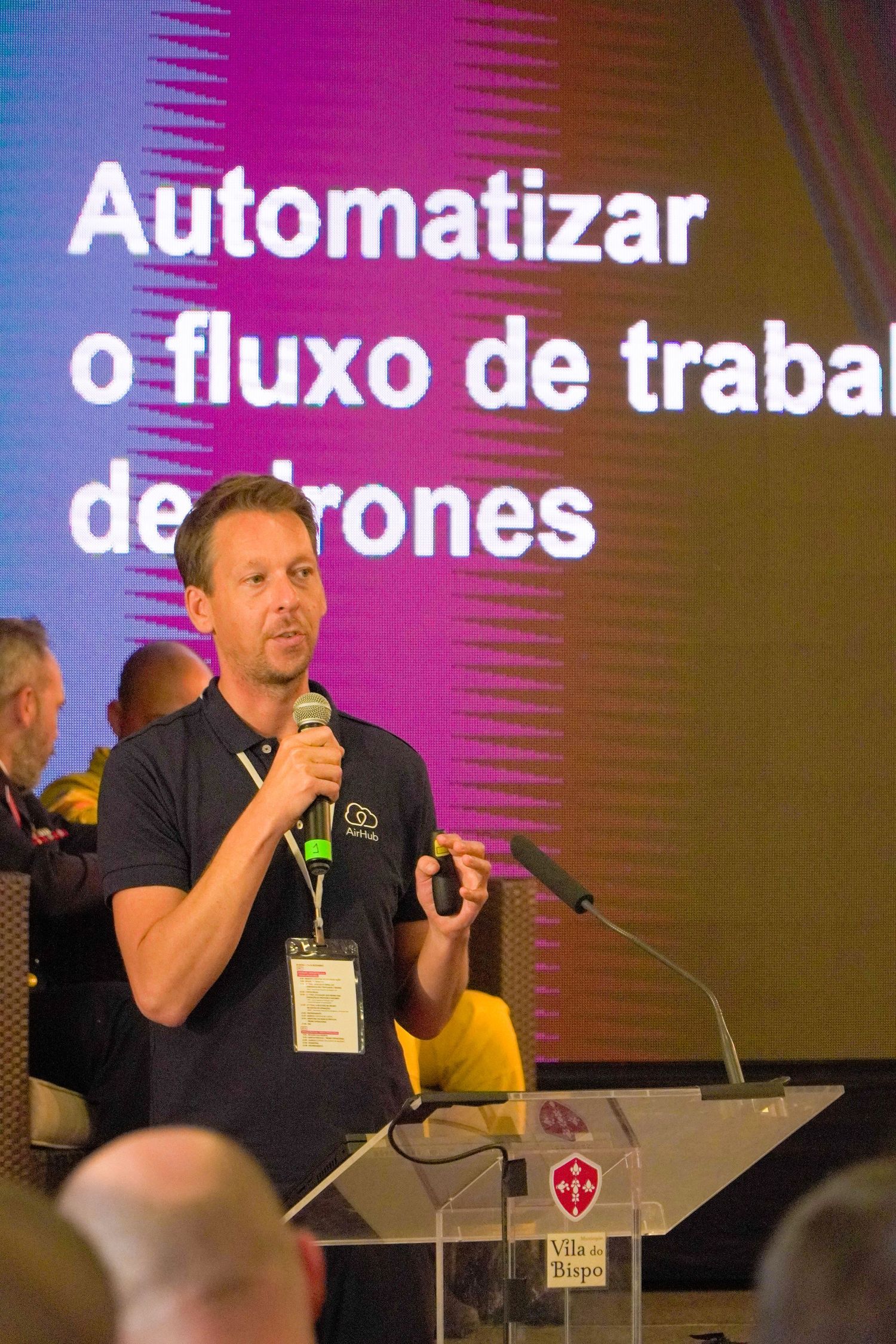 Conference presentation about automation with speakers on stage and projection screen.