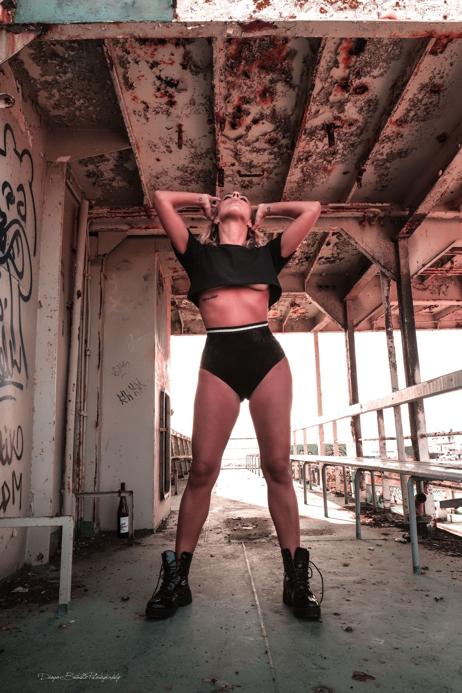 Artistic portrait of a figure in black athletic wear striking a pose in an abandoned industrial building setting.