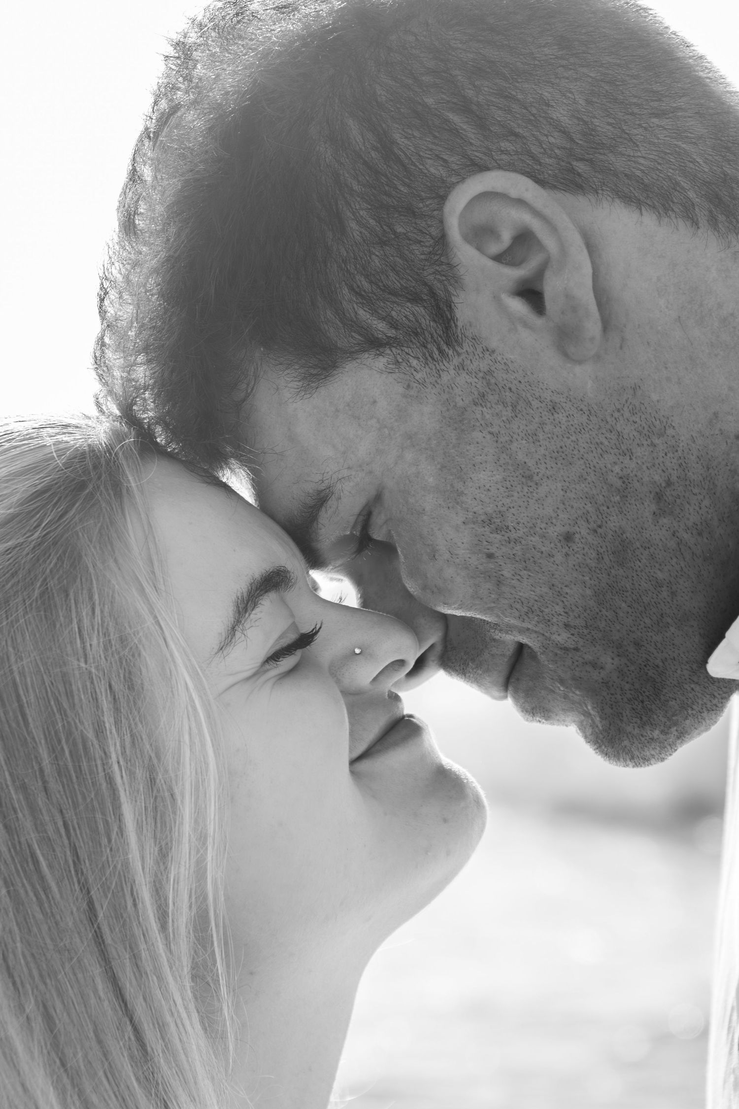 A romantic black and white intimate portrait showing two foreheads touching in a tender moment.
