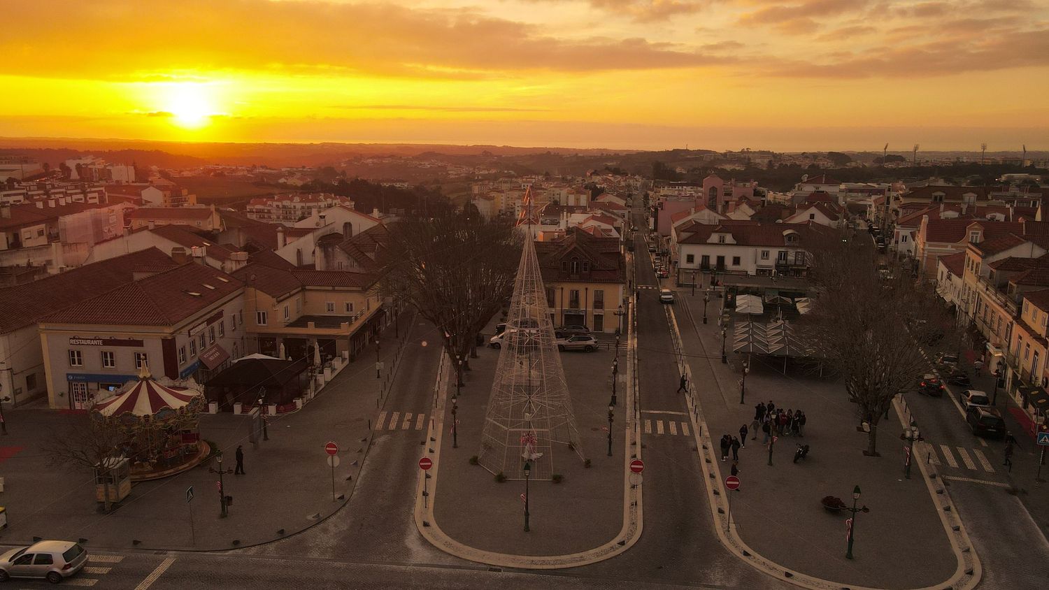 Aerial view of a European town square during golden sunset with rows of houses and roads stretching into the horizon.