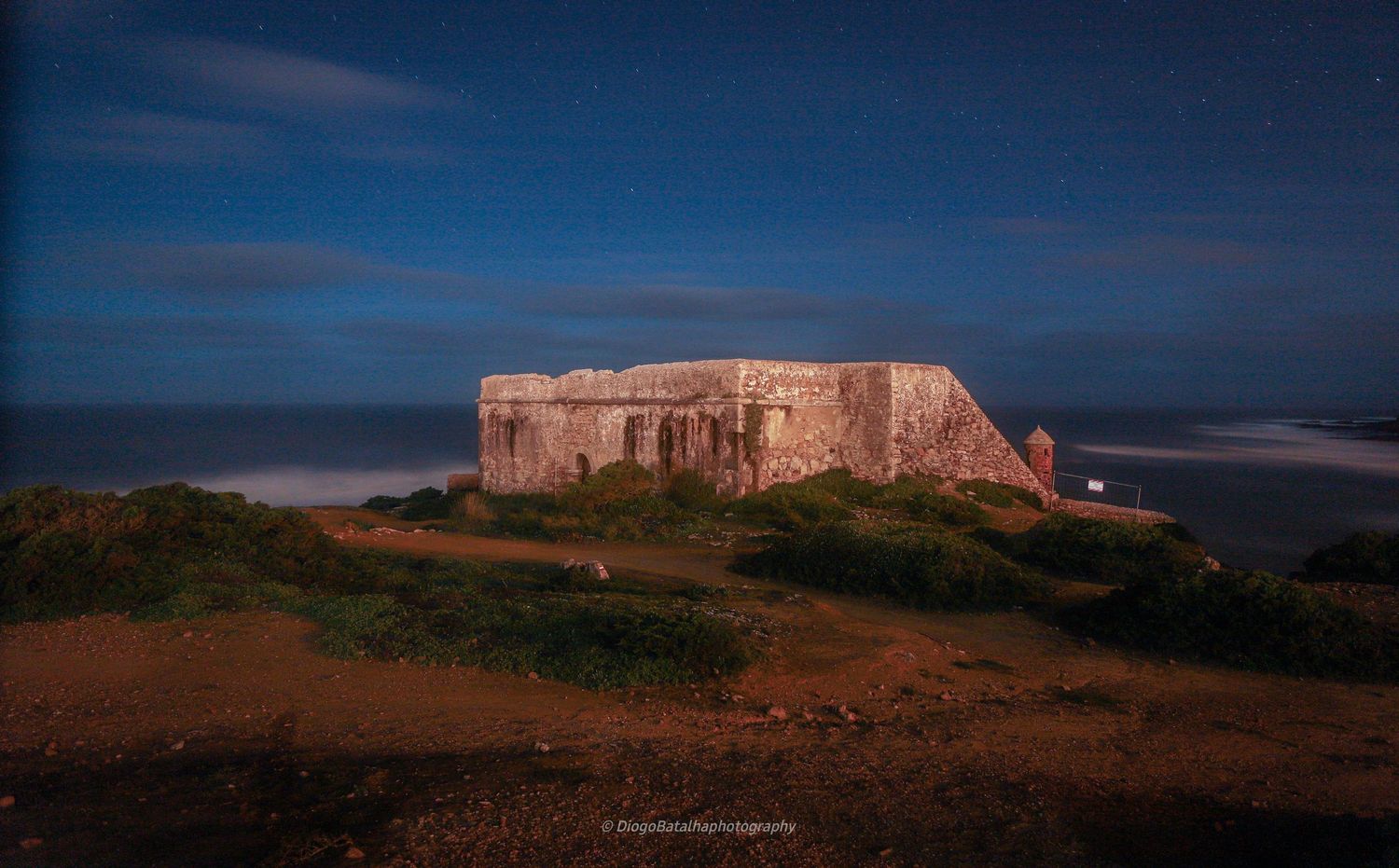 Old concrete military bunker or fortification on hilltop against moody night sky with low clouds.