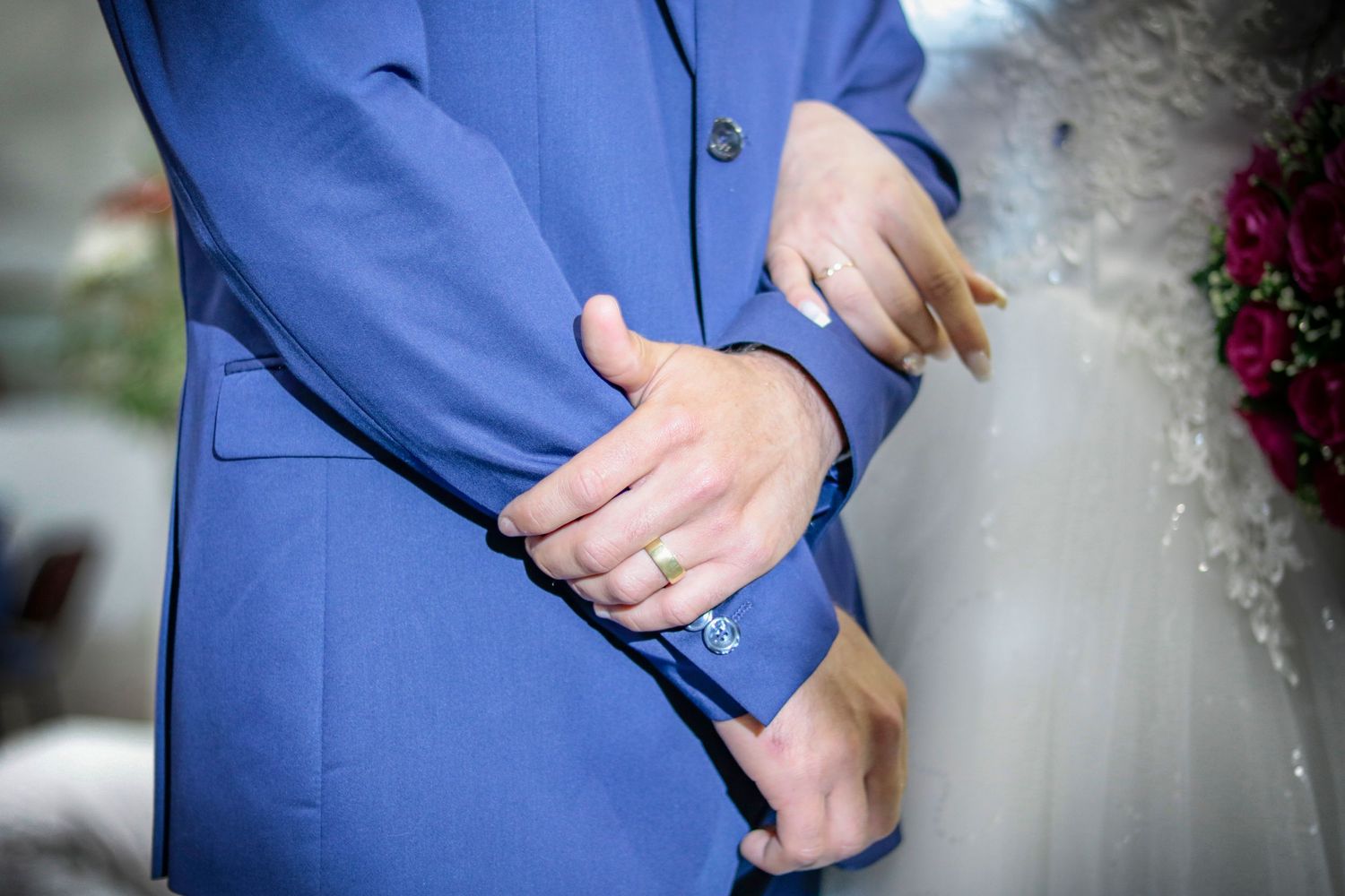 Detail shot of hands and formal attire during wedding ceremony.