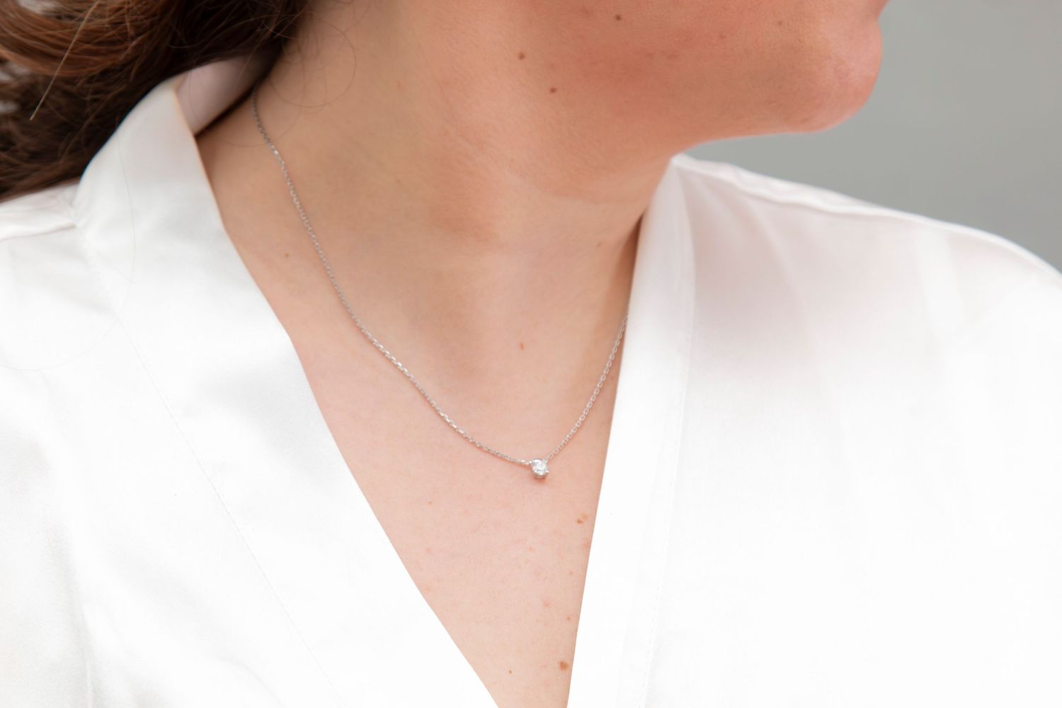 Delicate silver necklace worn with white bridal robe.