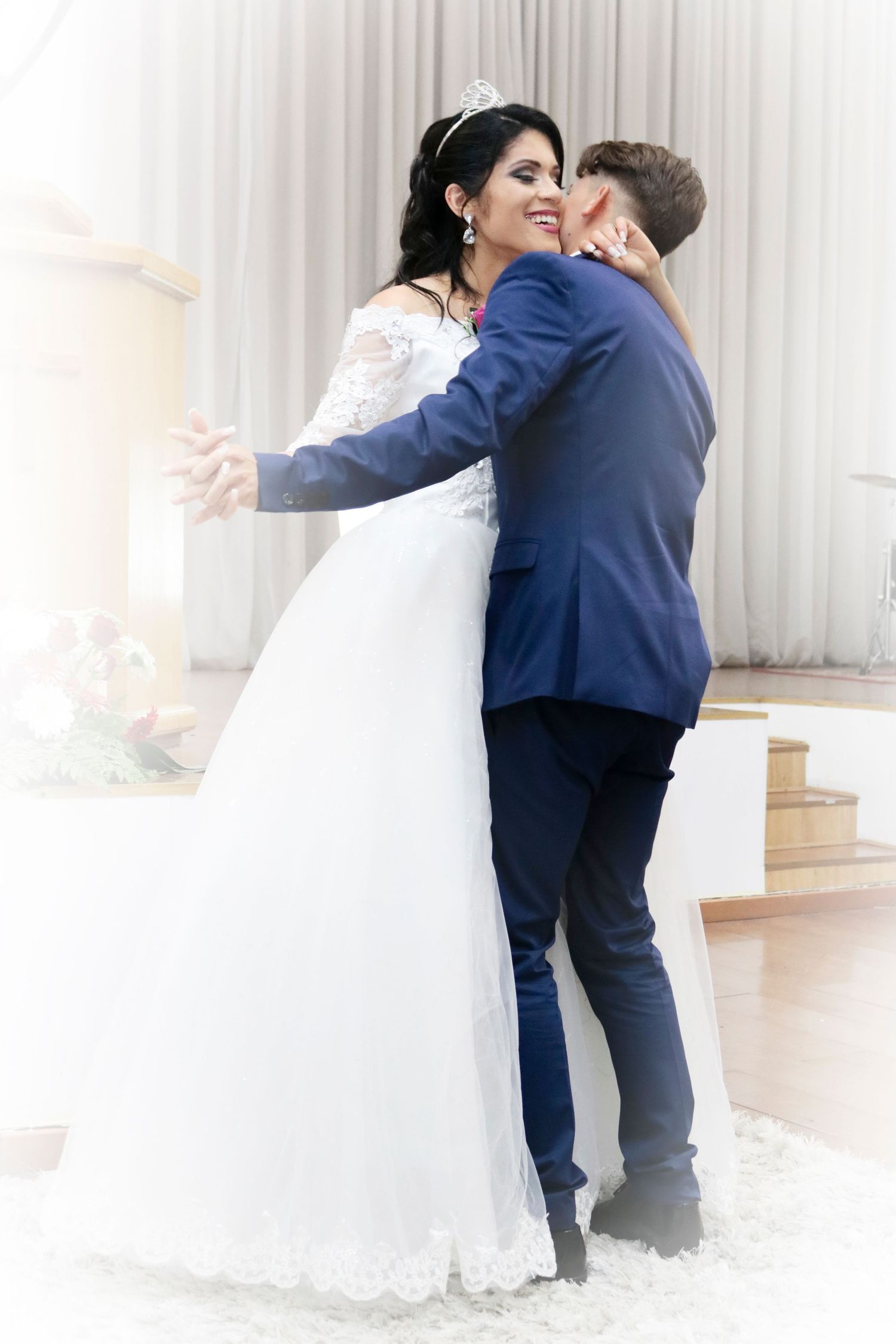 Intimate wedding moment with couple in white dress and navy suit embracing.