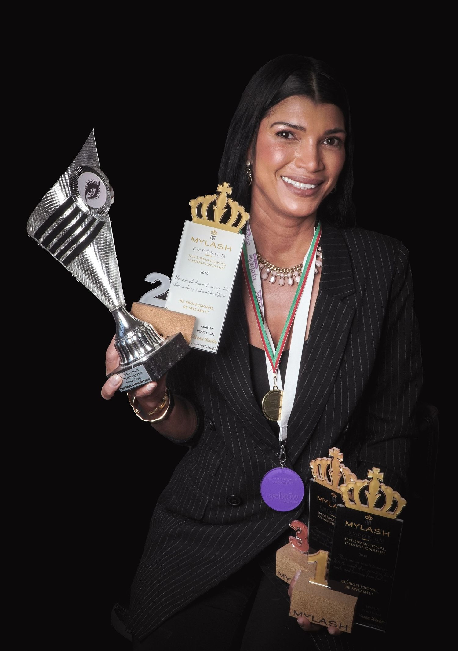Award winner displaying trophies and medals against black background.