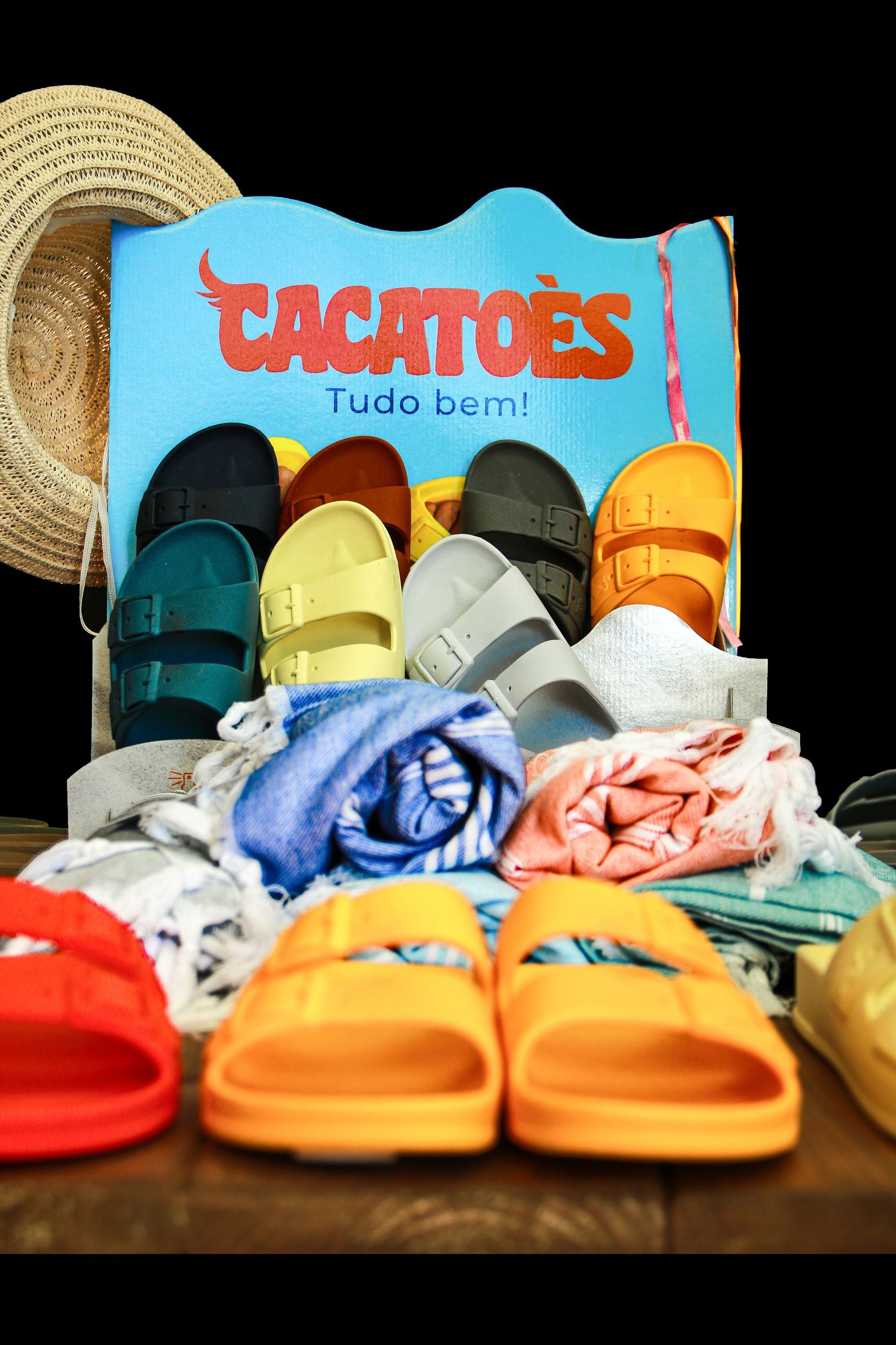 Colorful display of Cacatoes sandals and beach accessories with straw hat.