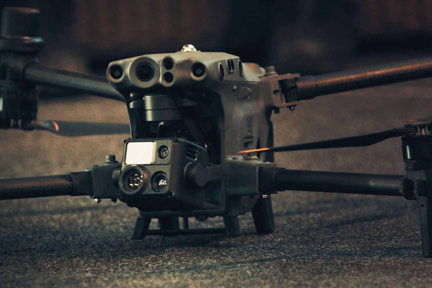 A military-style remote-controlled drone or UAV with propellers and mechanical components in dramatic lighting.
