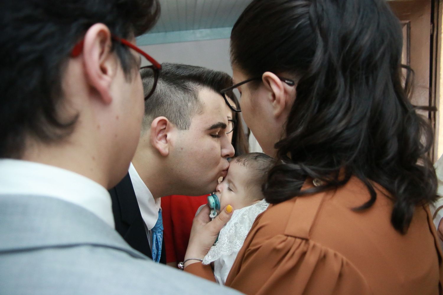 Intimate gathering at a baptismal ceremony with family members surrounding the baby.
