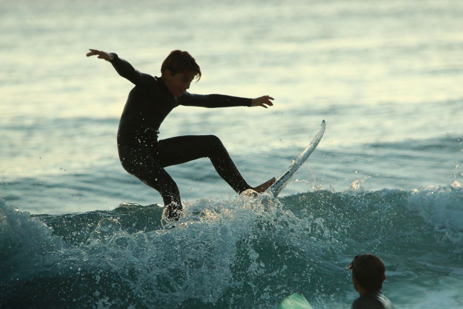 Surfer performing aerial maneuver on wave with dramatic splash.