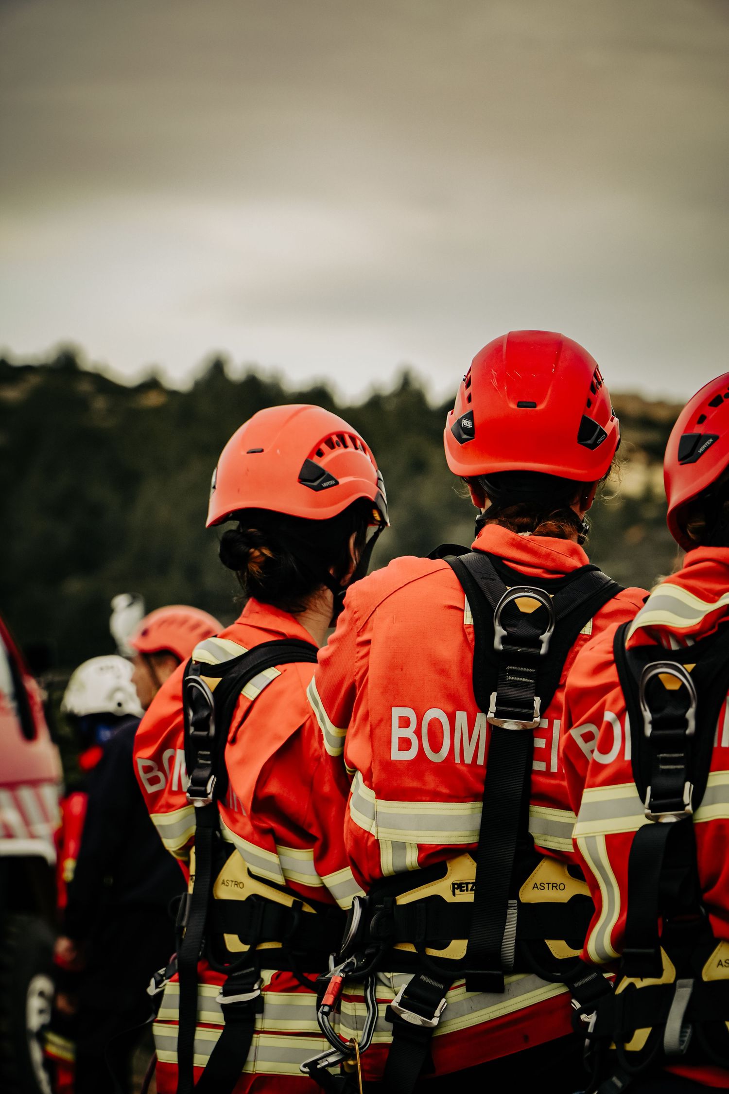 Firefighters wearing orange safety gear and red helmets stand in formation during an emergency response training exercise.