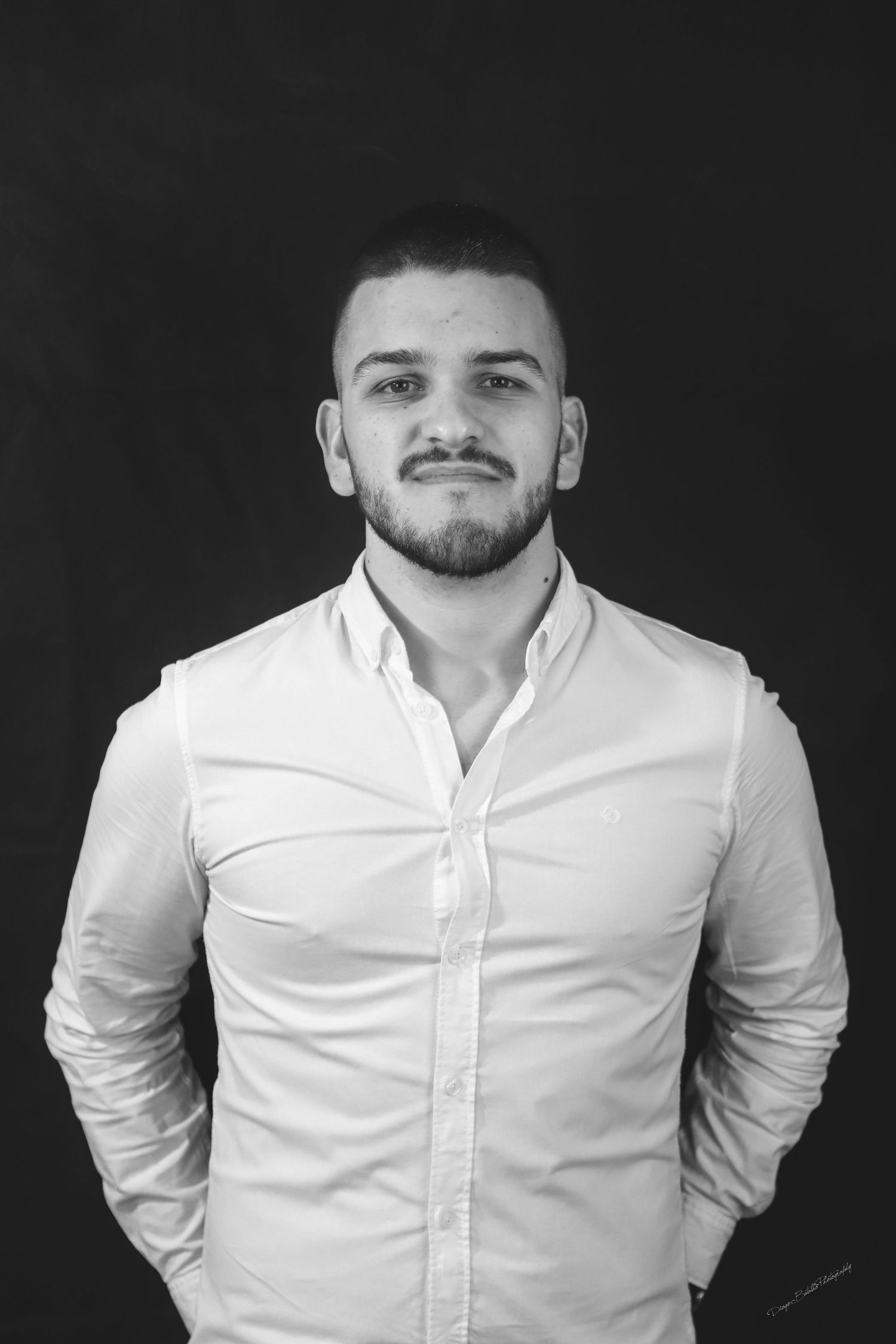 Black and white portrait of person in white button-down shirt against dark background.