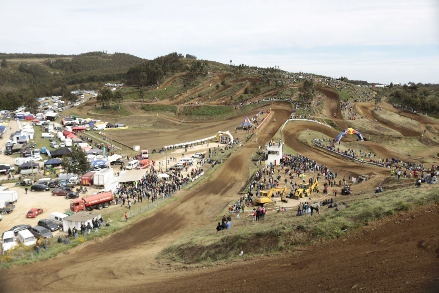 Aerial view of a motocross race track with spectators and tents scattered across hilly terrain.