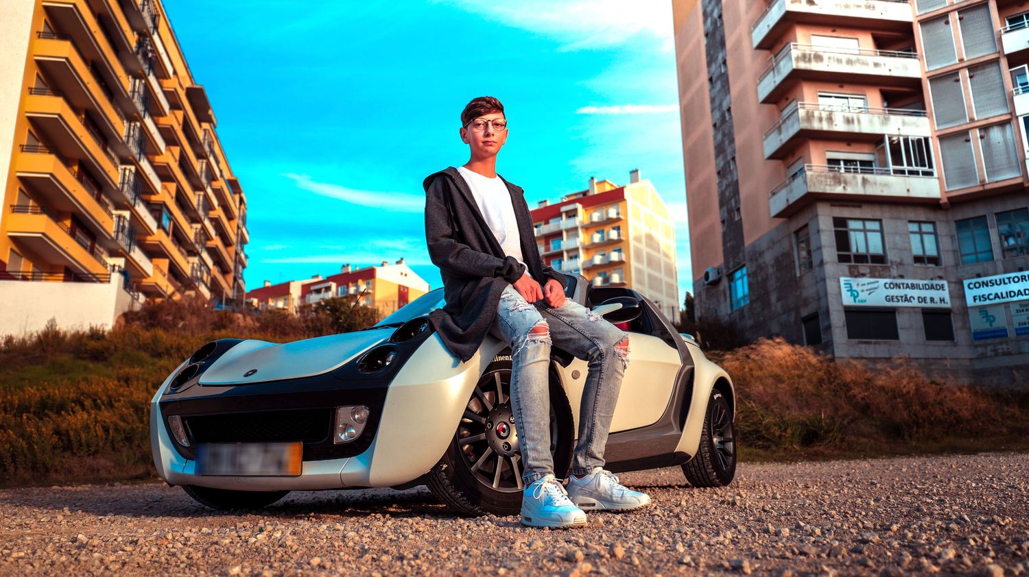Sleek white sports car parked in an urban setting with apartment buildings in the background.
