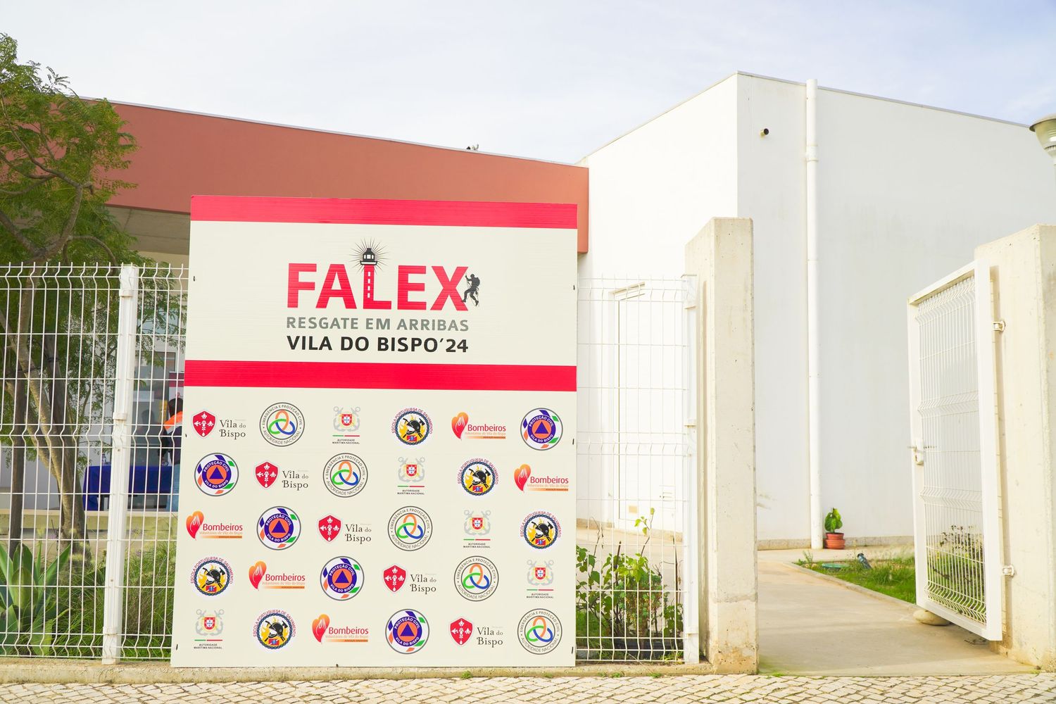 Exterior view of Falex building with logo wall displaying multiple partner organization emblems.