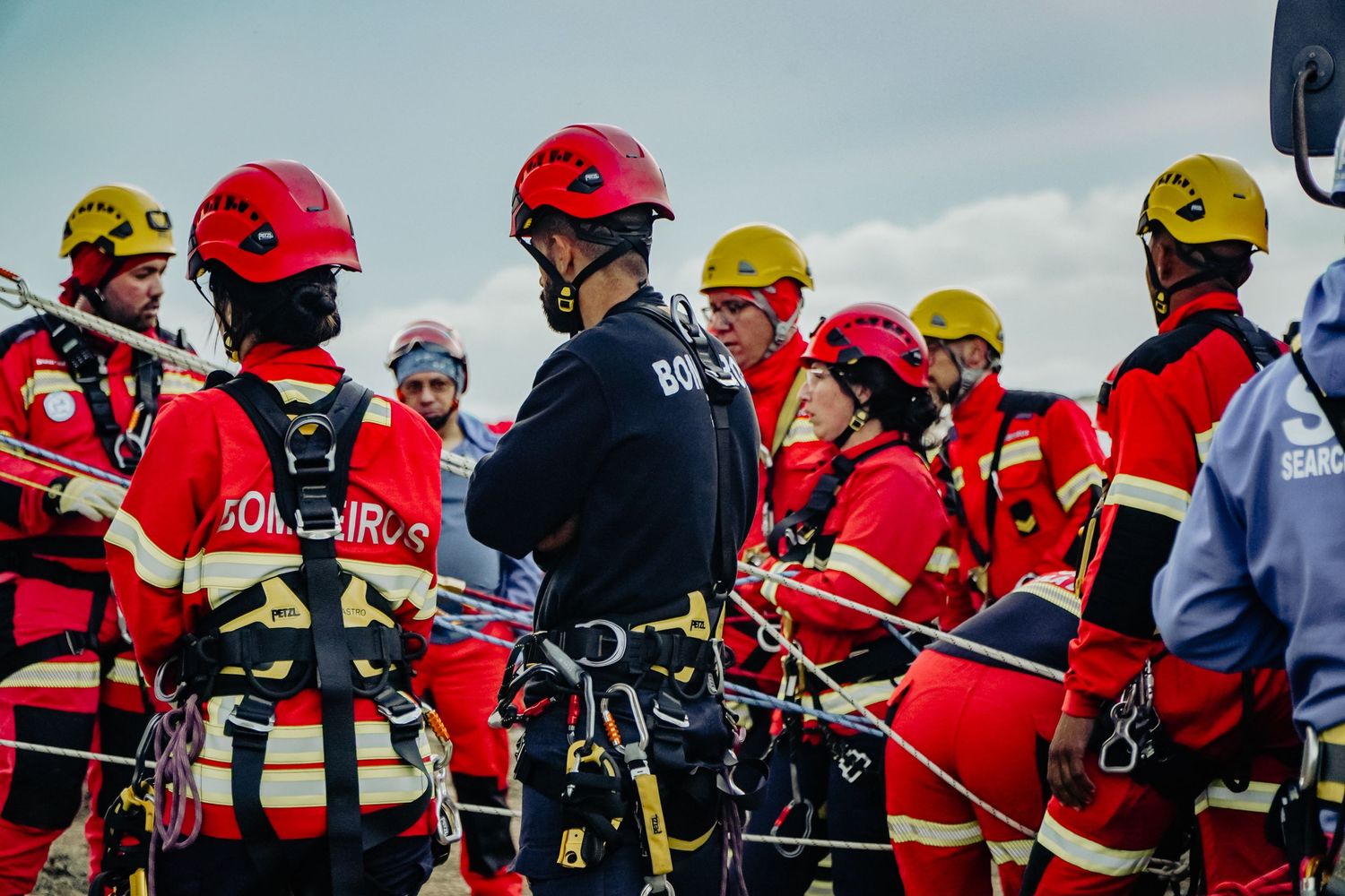 Group of rescue workers in red uniforms and safety helmets gathering for training or briefing.