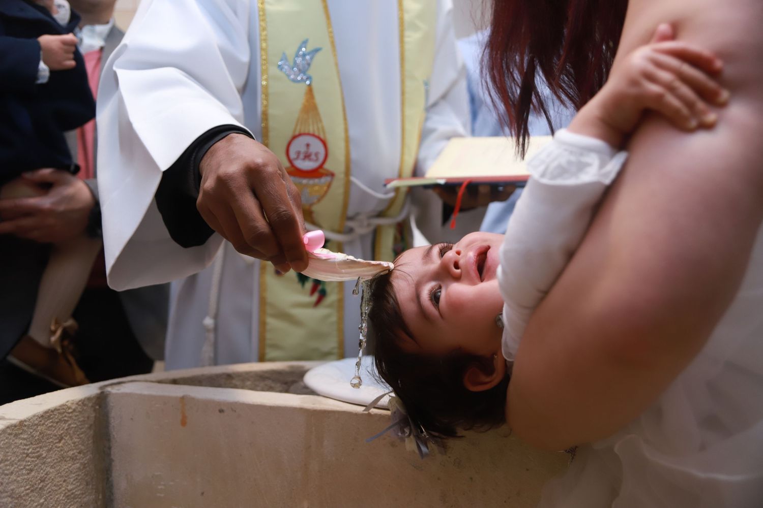 A baptism ceremony moment showing water being poured during the sacred ritual.