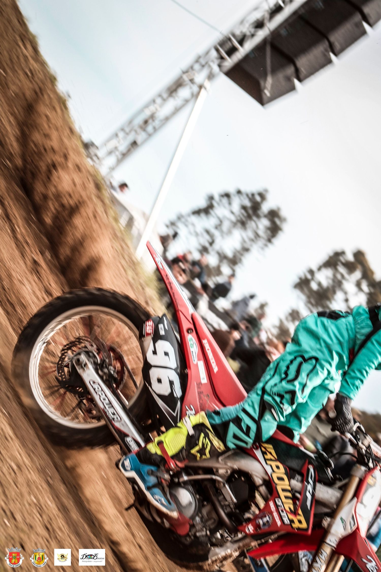 Dynamic low-angle shot of a motocross rider performing a steep climbing maneuver on a dirt track.