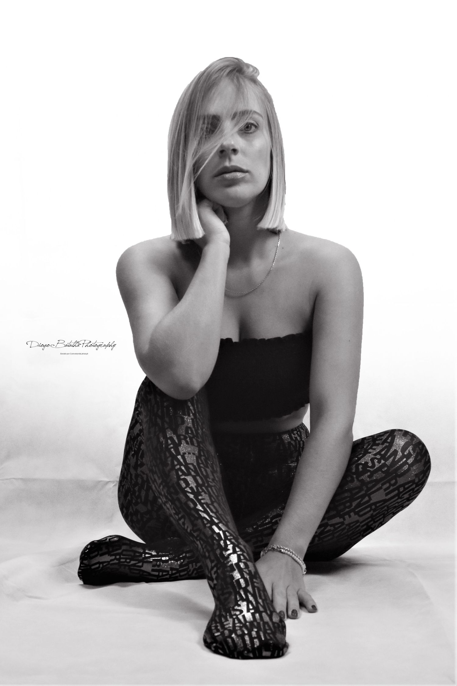 Artistic black and white portrait of person in black attire sitting on floor.