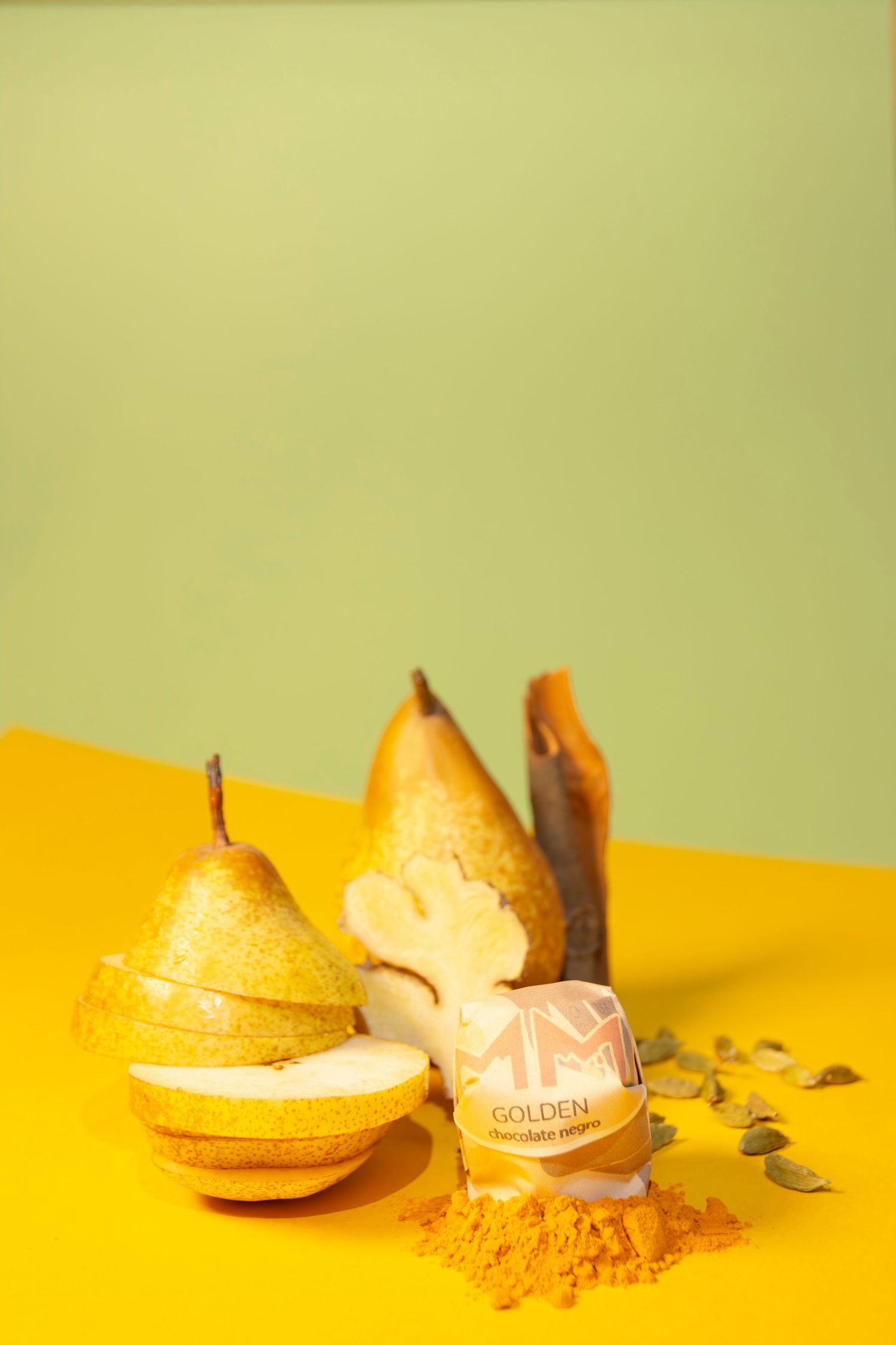 Sliced pears and golden spice powder arranged on a vibrant yellow surface against a mint green background.