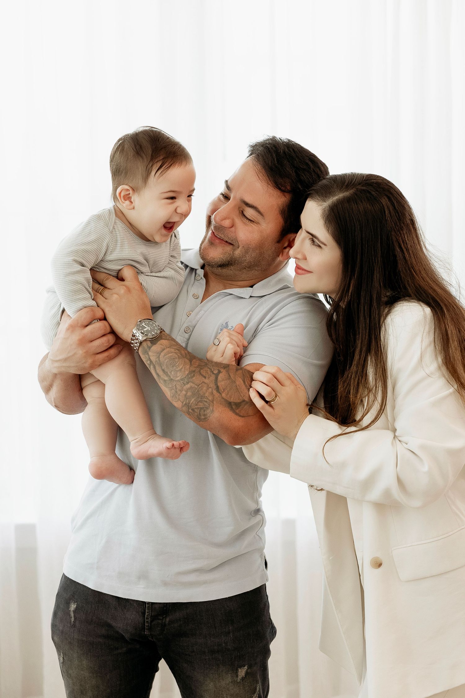 Happy family sharing a joyful moment together against white backdrop in casual indoor setting.