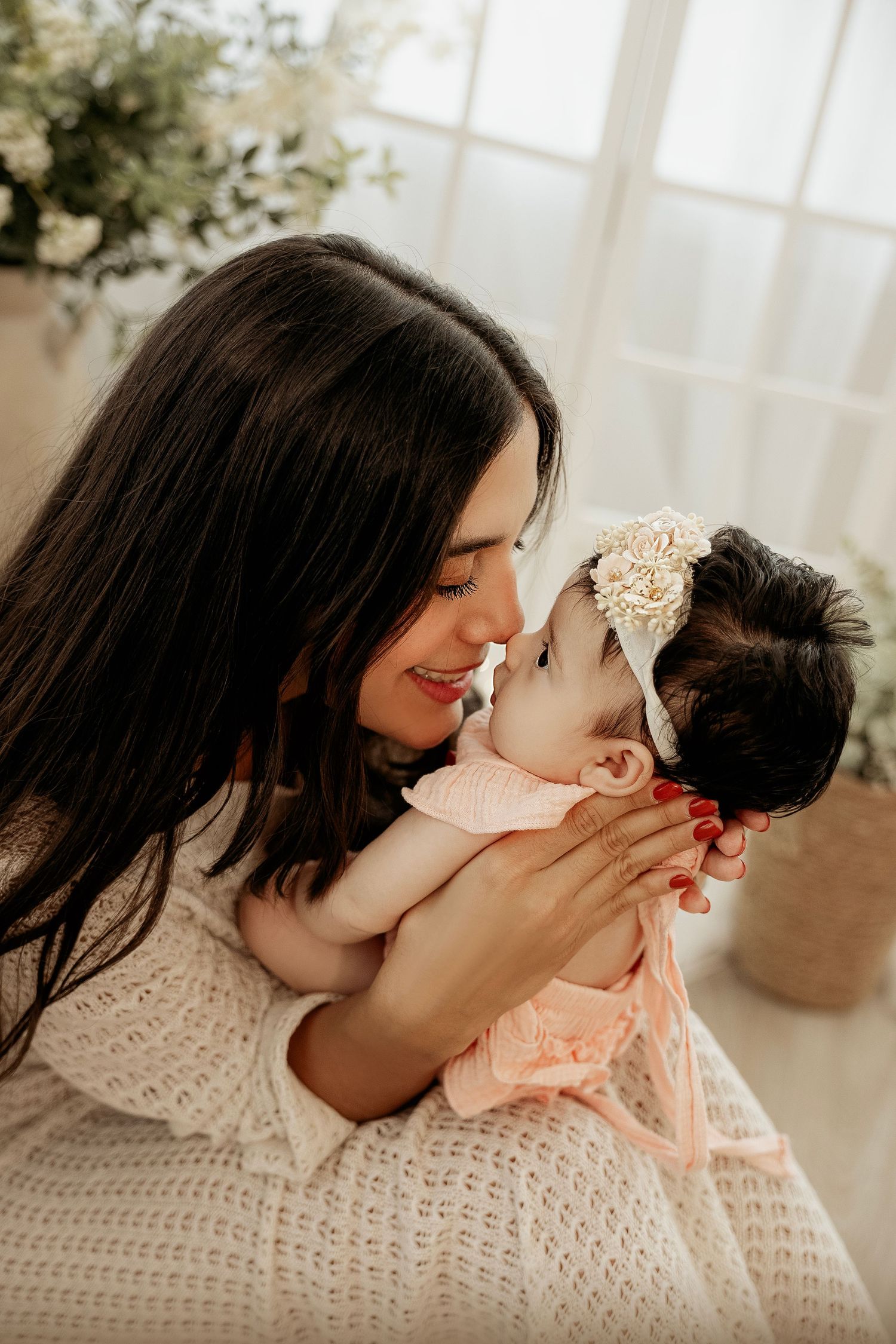 Sweet tender moment shared between parent and baby in a sun-filled room with warm natural light filtering through windows.