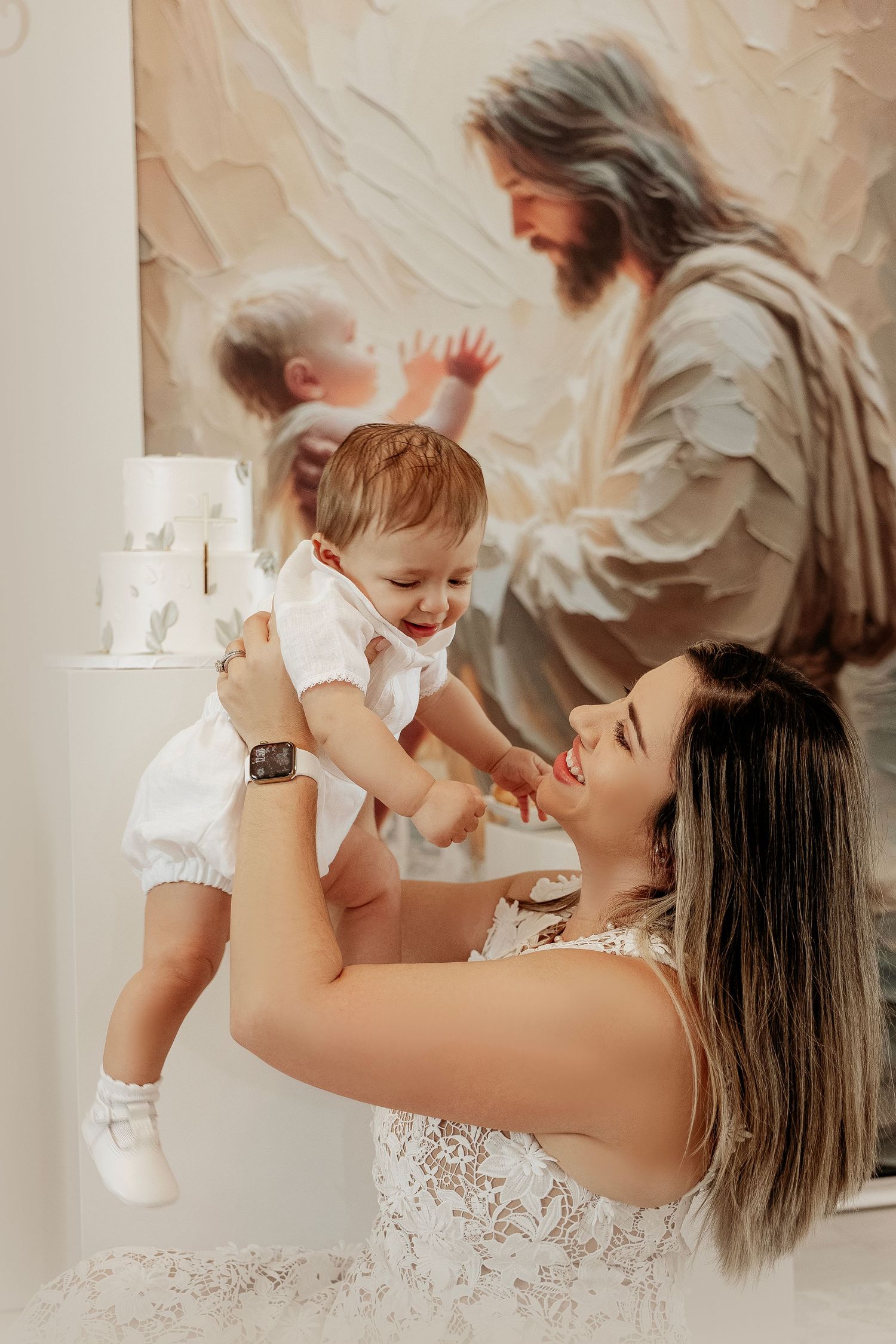 A tender moment captured in soft beige tones as a parent lifts and plays with a joyful baby wearing white.