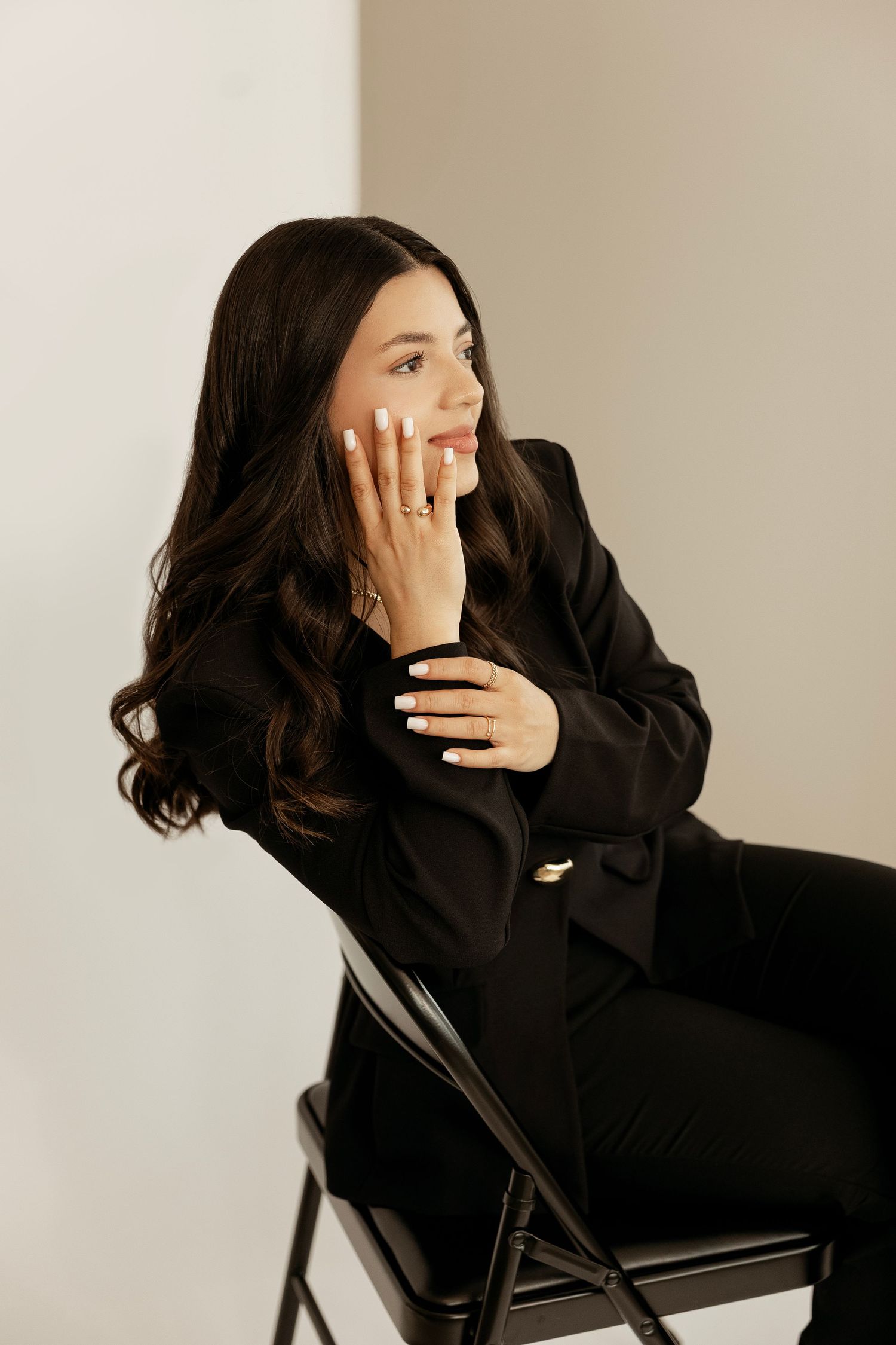 Person in black turtleneck sweater sits in chair and covers face with hands in artistic portrait series.