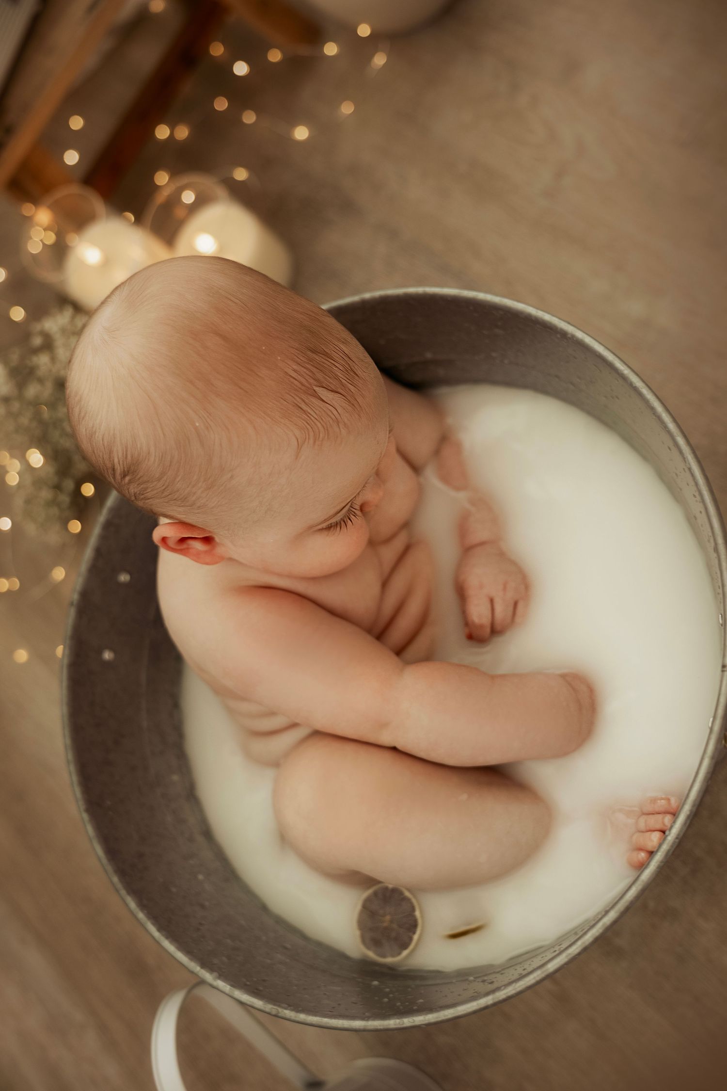 A series of artistic newborn photography poses in a milk bath with soft lighting and bokeh effects in the background.