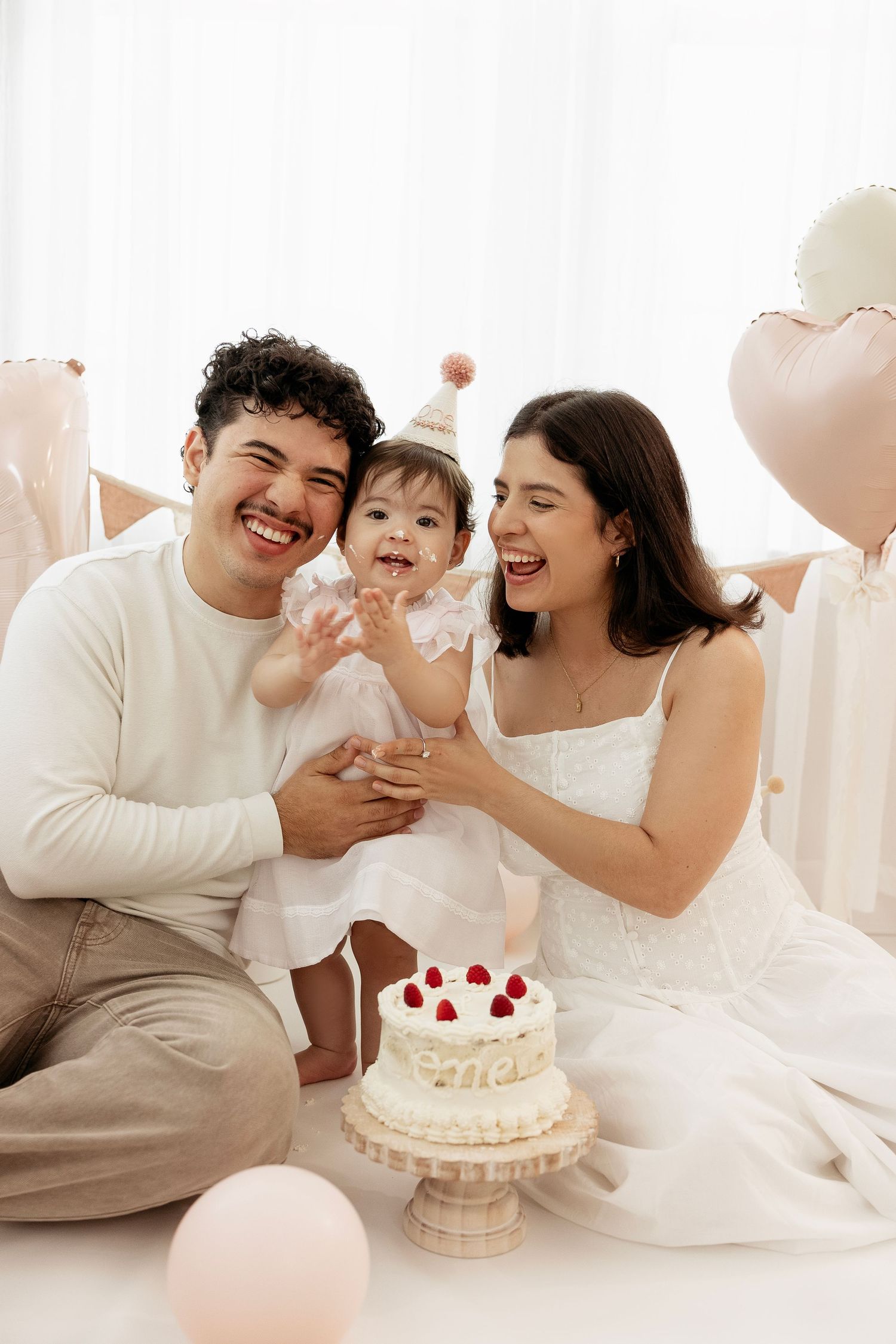 Family in white outfits sharing joyful moments while enjoying cake together in bright setting.