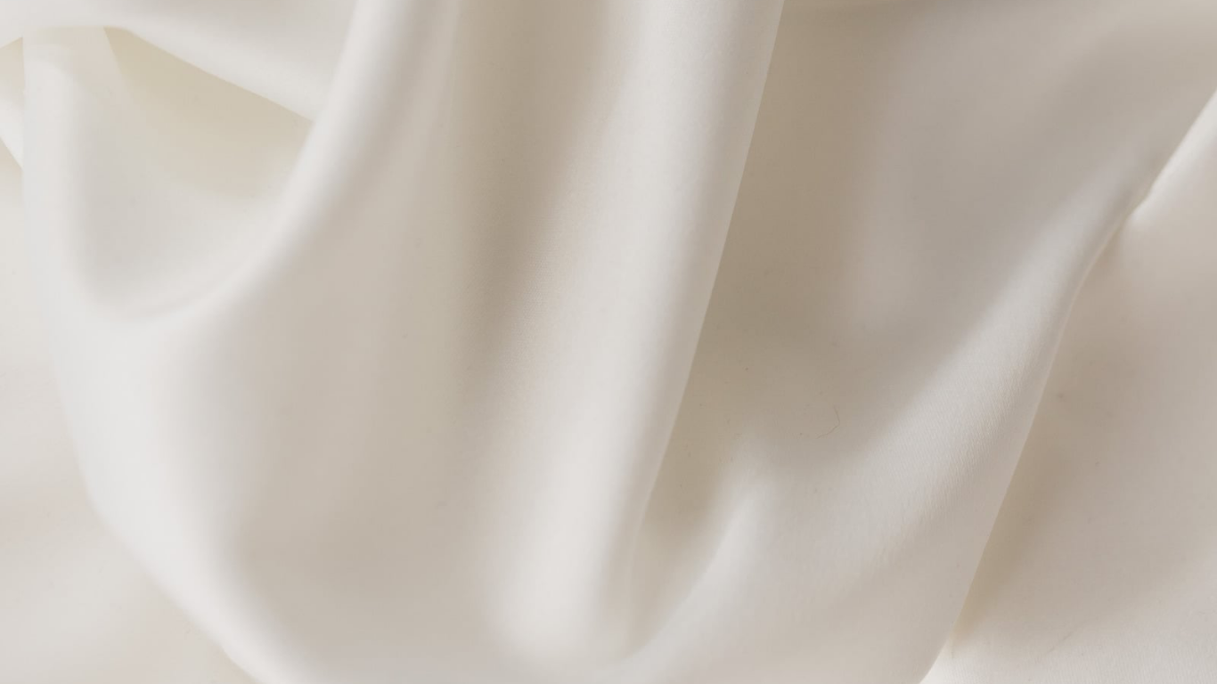 Soft white silk fabric with elegant flowing folds and smooth luxurious texture, perfect for fashion or interior design.