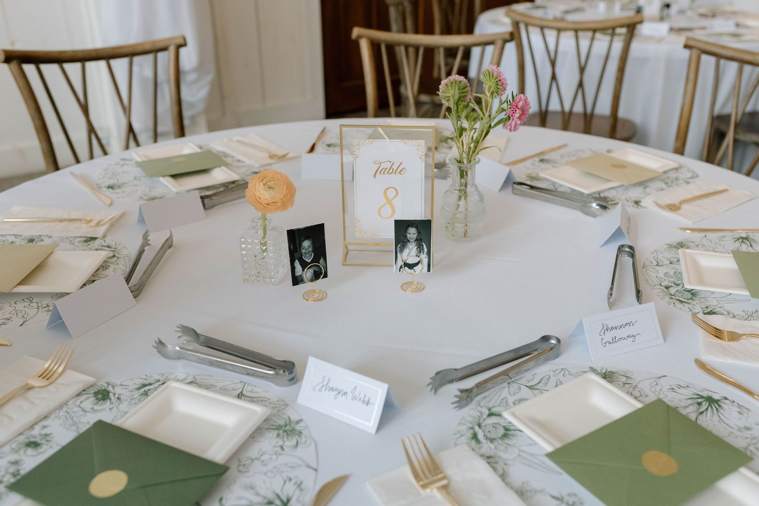 Elegant wedding reception table with green envelopes, gold flatware, floral centerpiece, and vintage photo decorations.