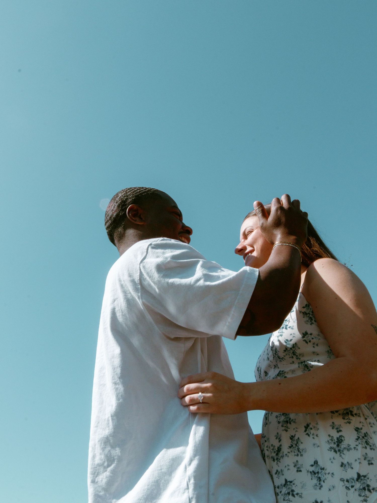 Two people dance together against a bright blue sky background.